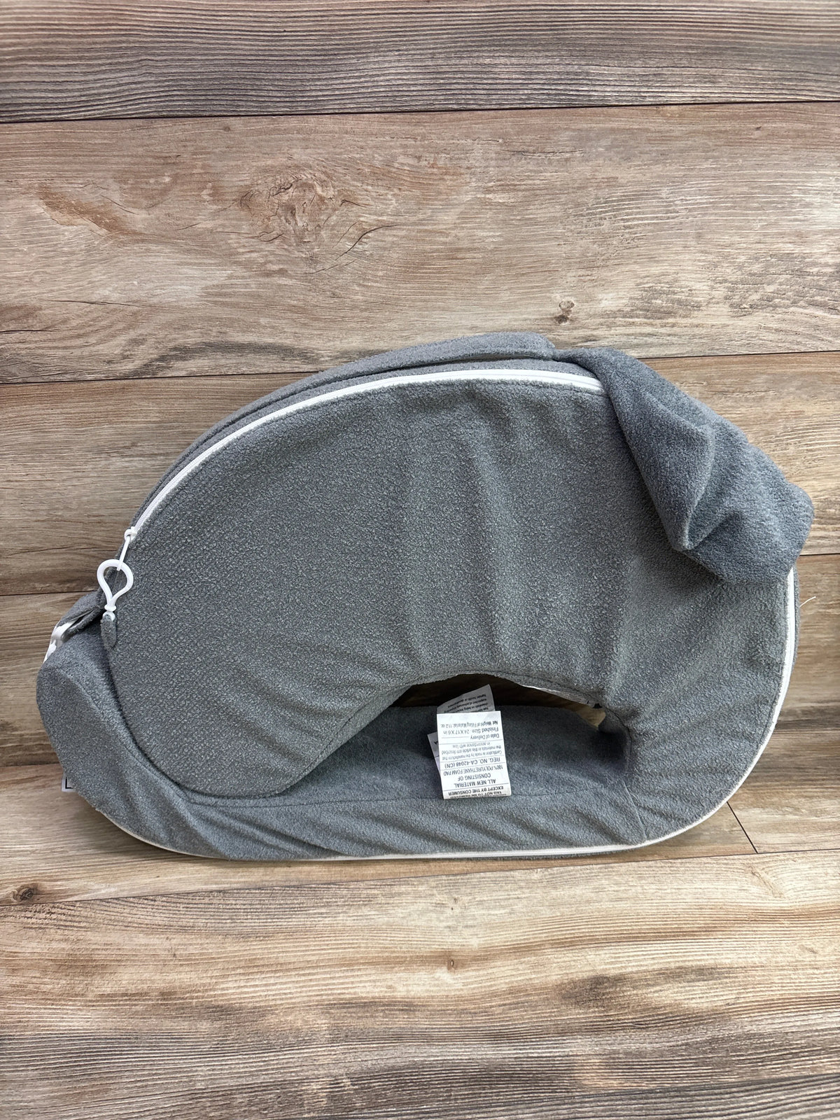 Top view of My Brest Friend nursing pillow in grey showcasing its curved shape and zippered cover on a wood surface