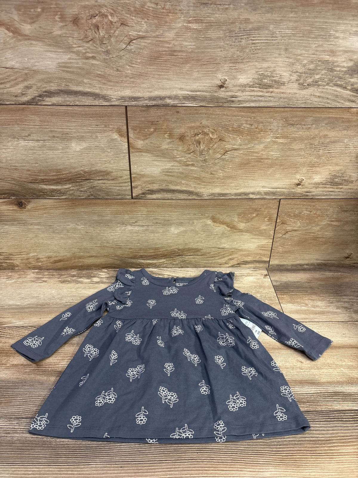 Front view of gray Okie Dokie long-sleeve dress, size 12 months, with white floral print and gathered waist on wood planks
