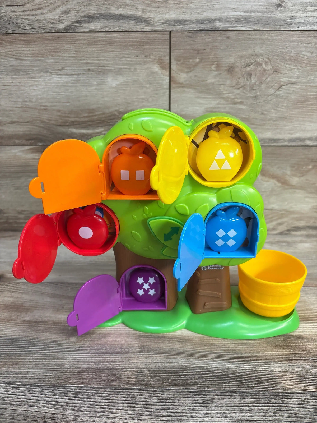 Front view of Learning Resources Hide & Seek Learning Treehouse with five colorful shape-matching apples and open doors