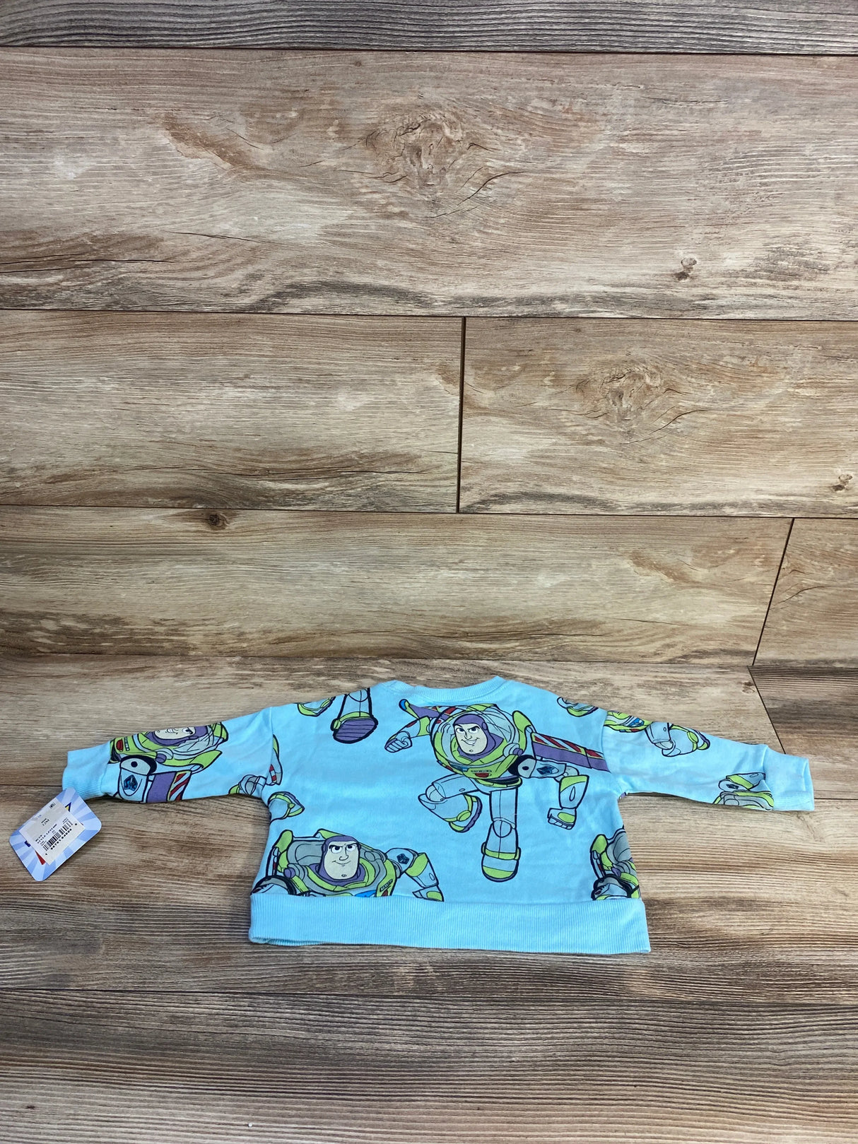 Blue baby sweatshirt with cartoon astronaut pattern on wooden background