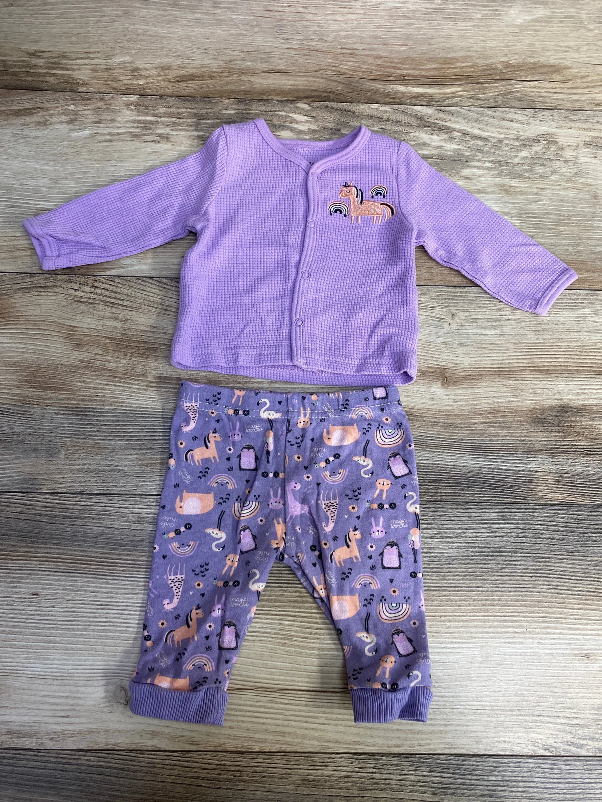 Purple baby outfit with long sleeve shirt and animal pattern pants on wood background
