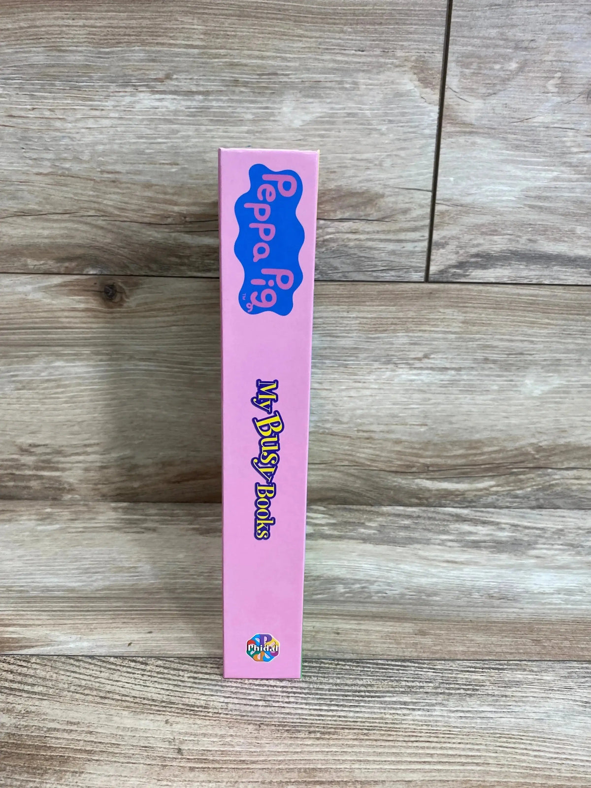 Side view of Peppa Pig My Busy Books box spine showing pink spine with Peppa Pig logo and My Busy Books title on wood background