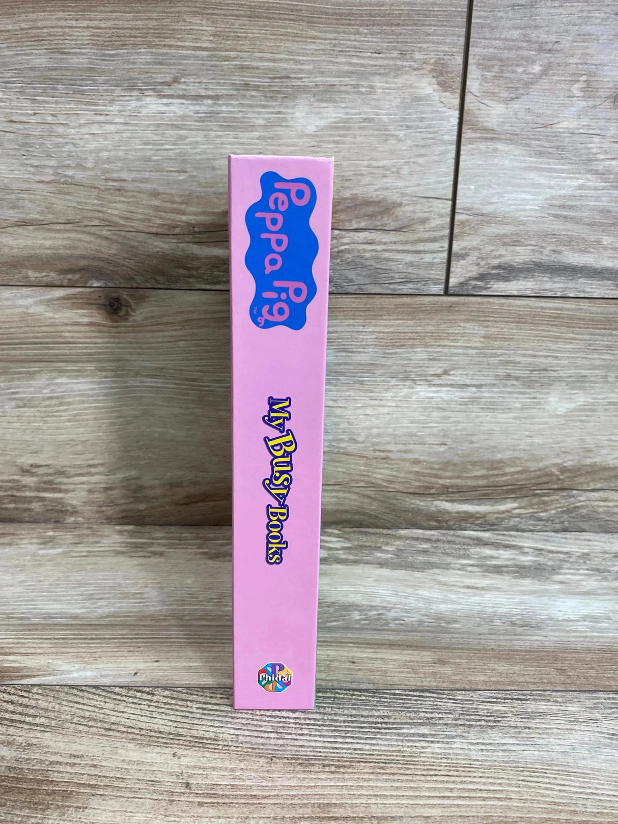 Side view of Peppa Pig My Busy Books box spine showing pink spine with Peppa Pig logo and My Busy Books title on wood background