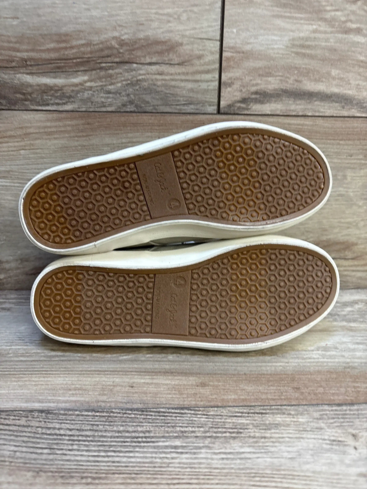 Bottom view of Cat & Jack Jakob boots (child size 4Y) showing brown honeycomb rubber outsoles and white sidewalls on wood floor