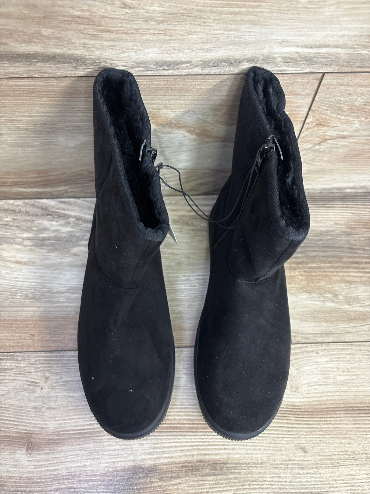 Pair of black suede kids boots with faux fur lining on wood floor