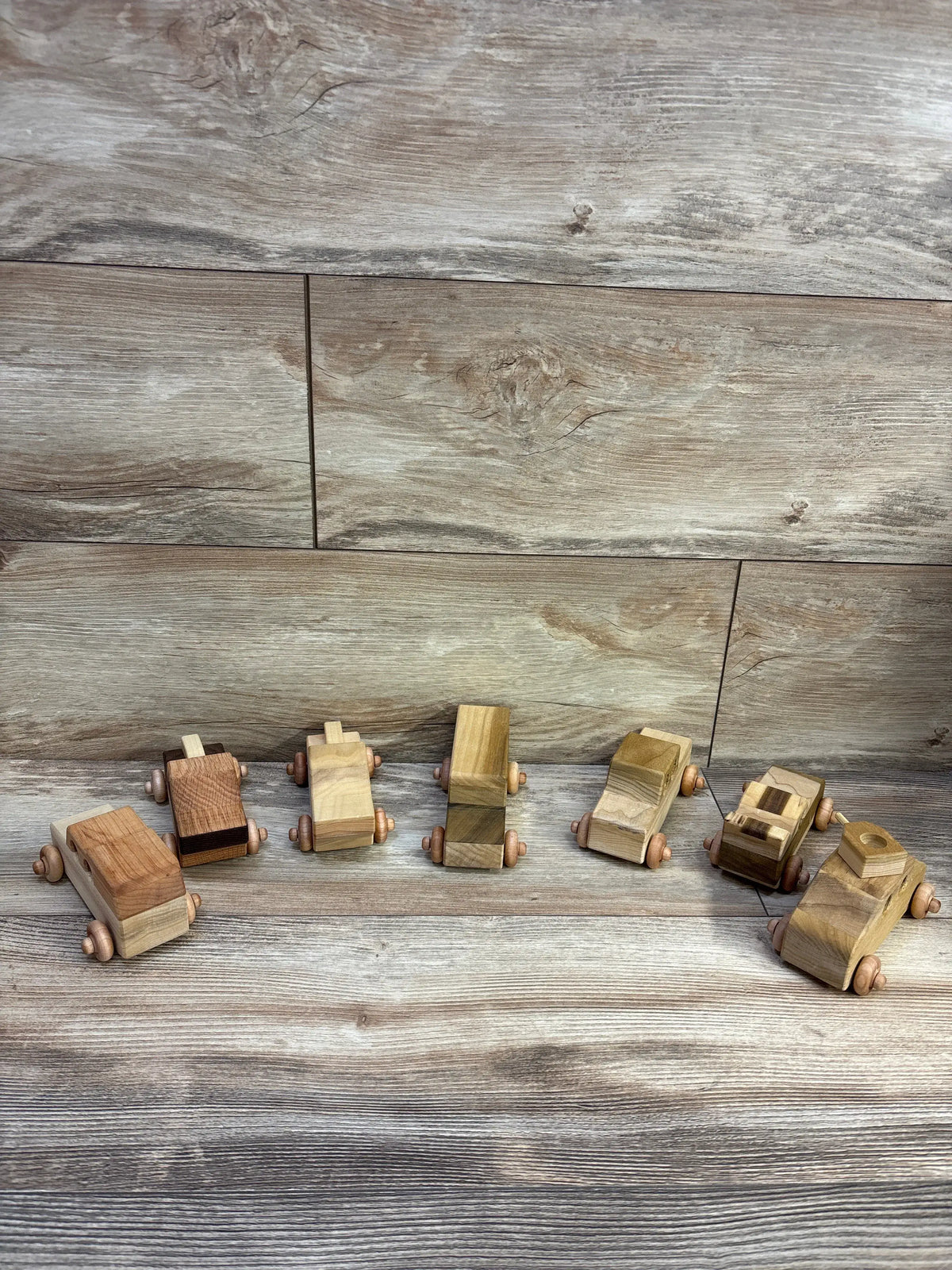 Display view of Toys4Kids wooden vehicles seven-piece set showcasing assorted natural wood designs on a wood-patterned background