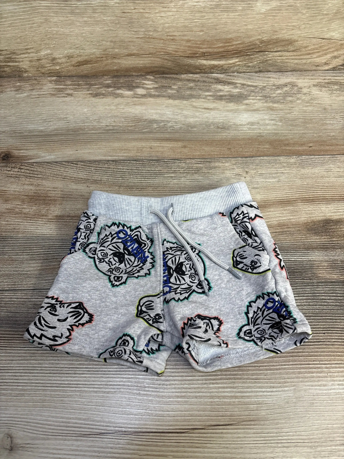 Top-down of grey Kenzo Kids cotton shorts with multicolor tiger print, elastic drawstring waistband on wood background