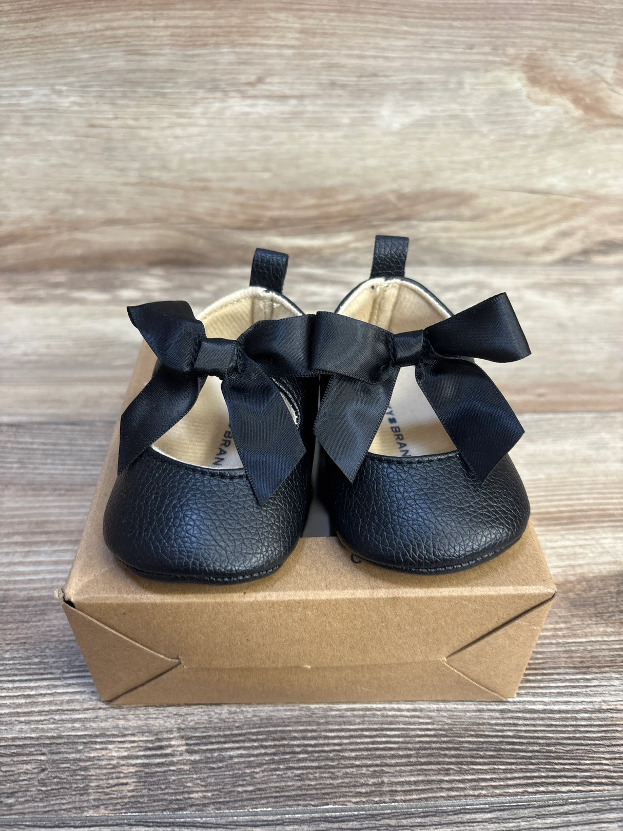 Black baby Mary Jane shoes with bows, soft sole for infants, displayed on box