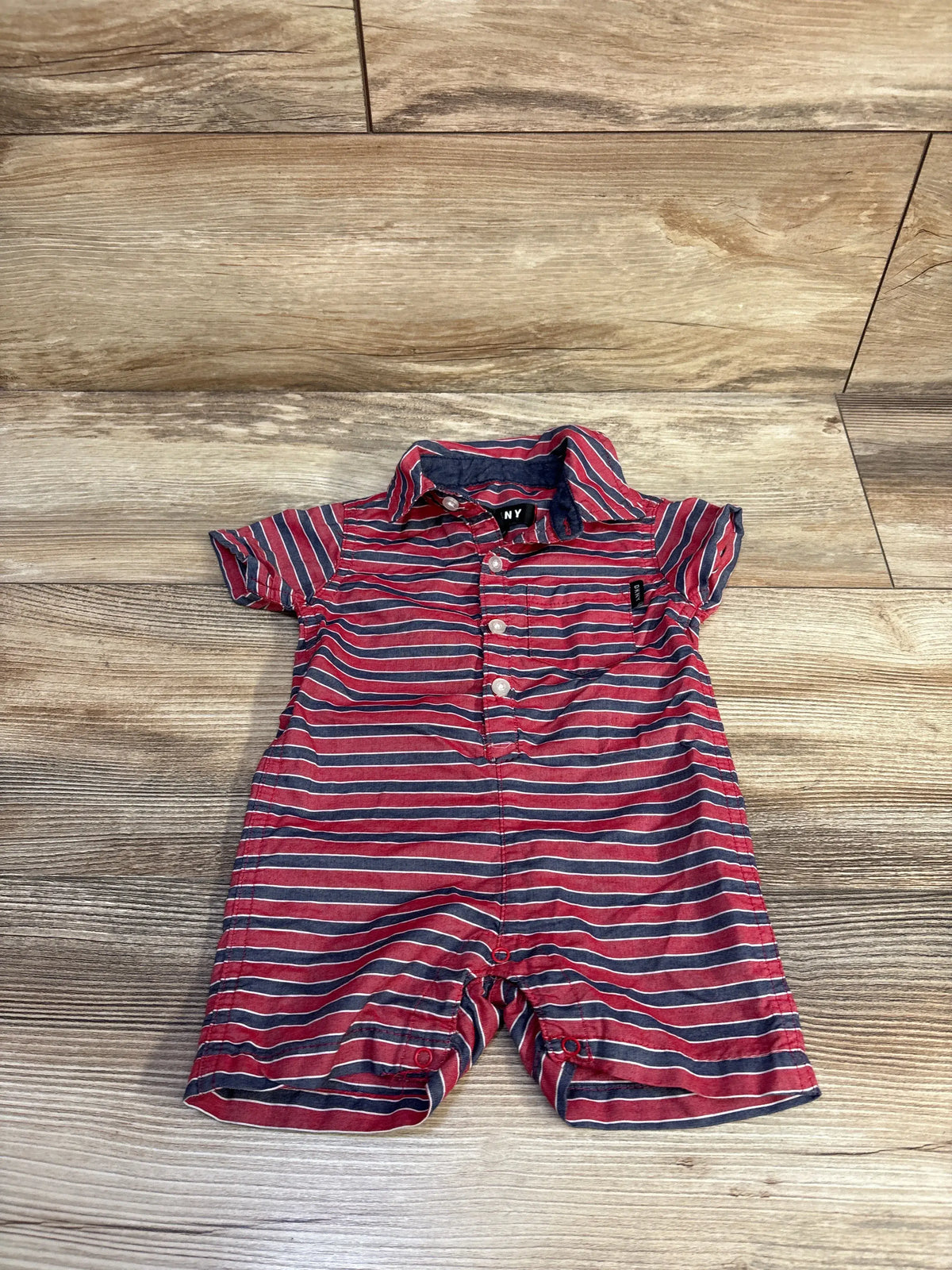 Front view of DKNY red striped polo shortie romper showcasing collar and short sleeves on a wood floor