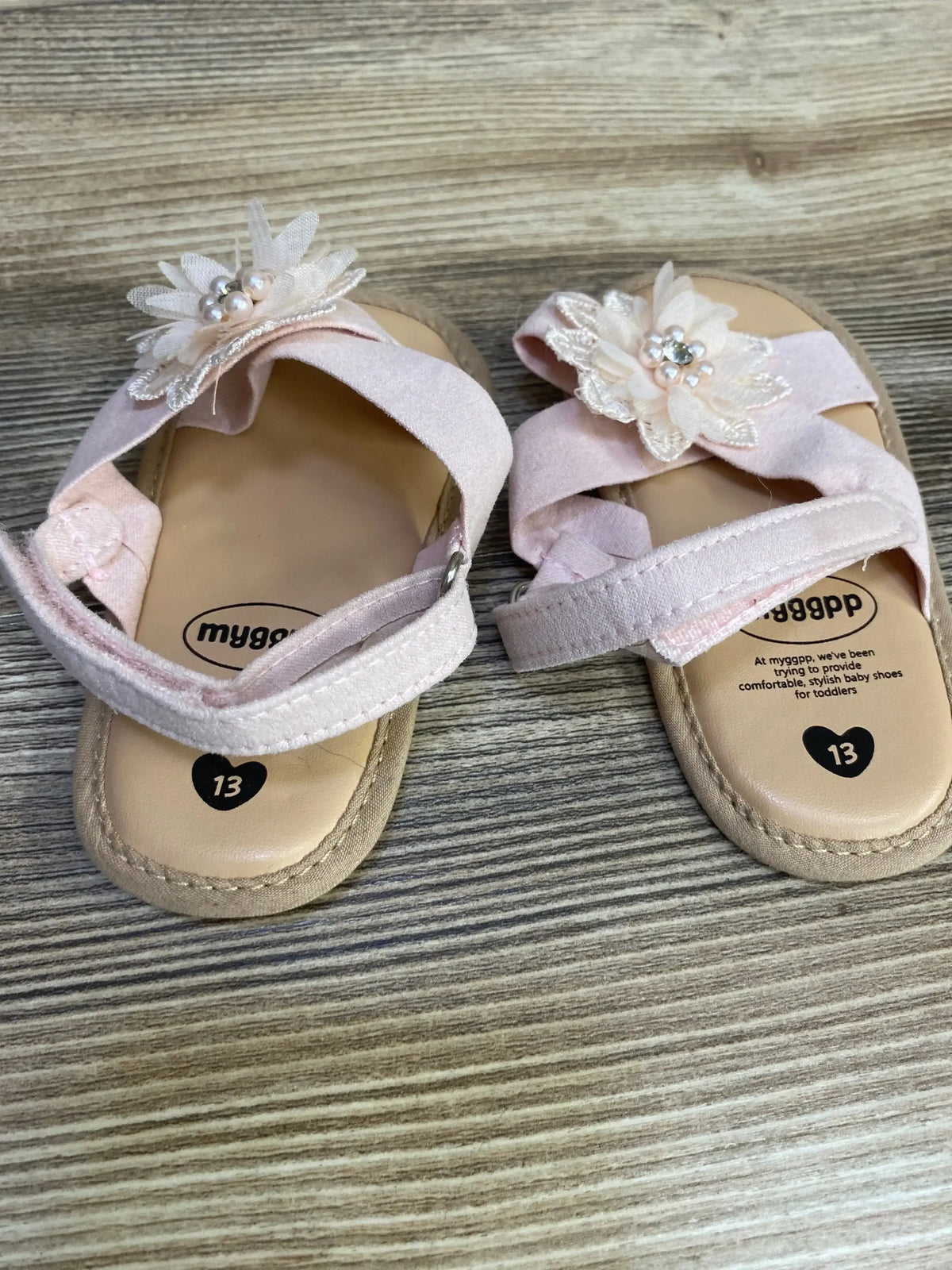 Front view of pink cross-strap toddler sandals showcasing pearl embellishments with white background