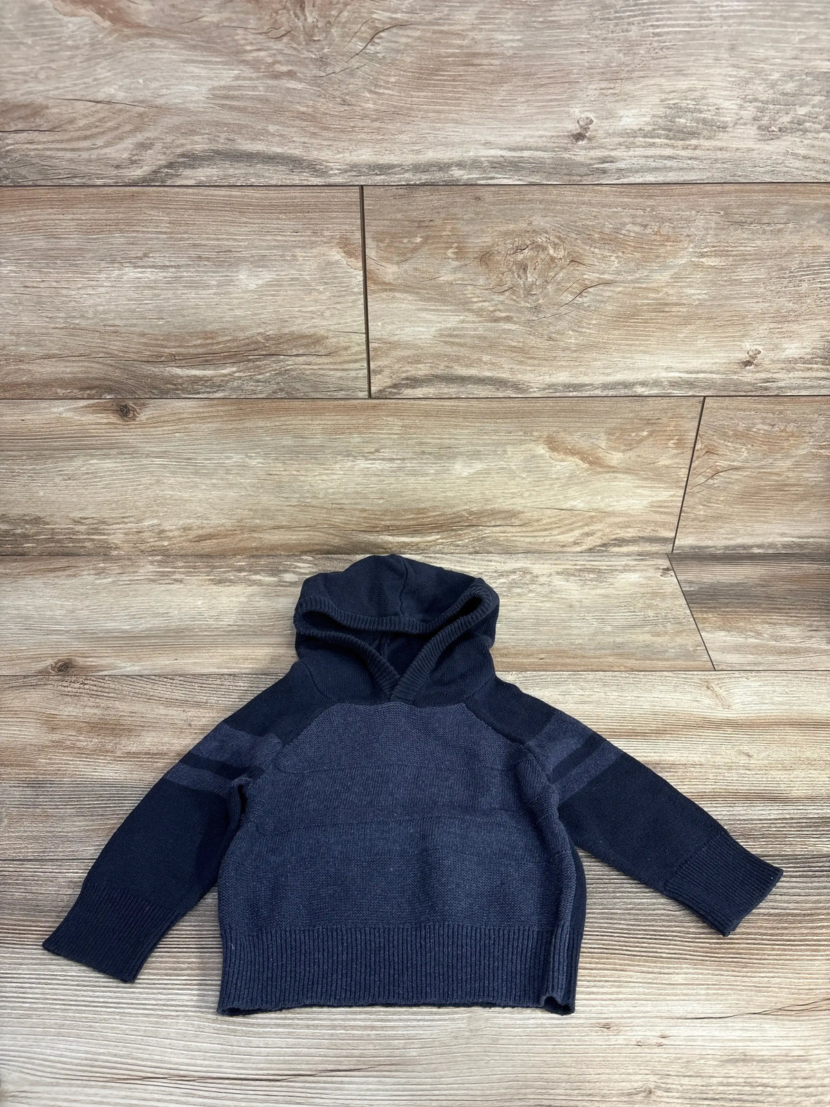 Navy blue toddler hooded sweater with long sleeves on wood background