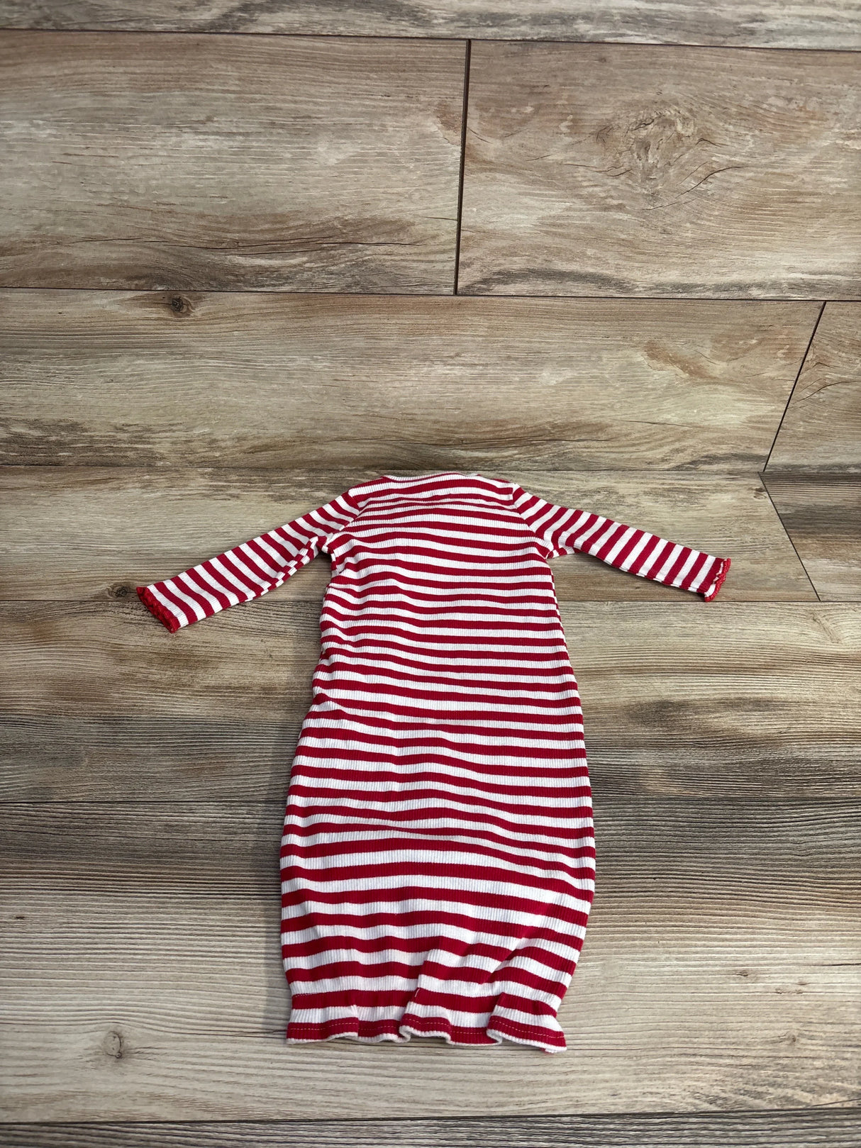 Flat-lay of Mudpie ribbed sleeper gown size 0-3M showing red and white stripes, long sleeves and cinched bottom on wood floor