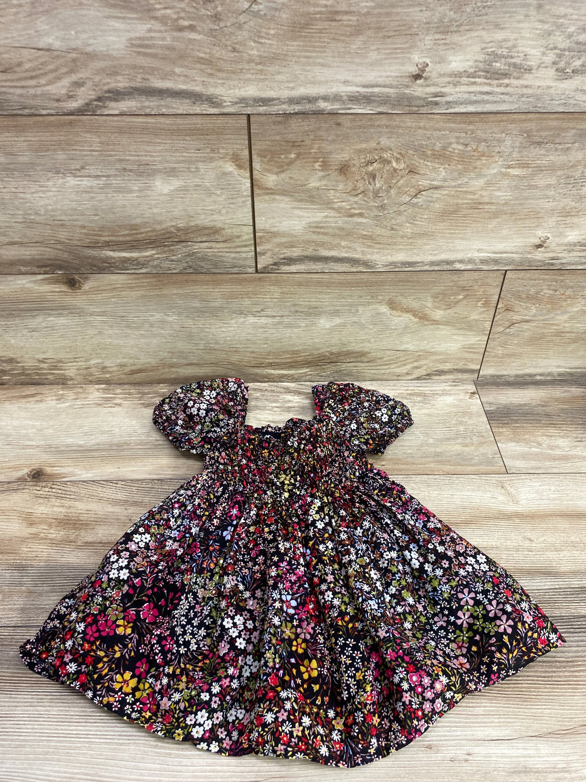 Baby Gap black floral smocked puff sleeve baby dress on a wooden surface