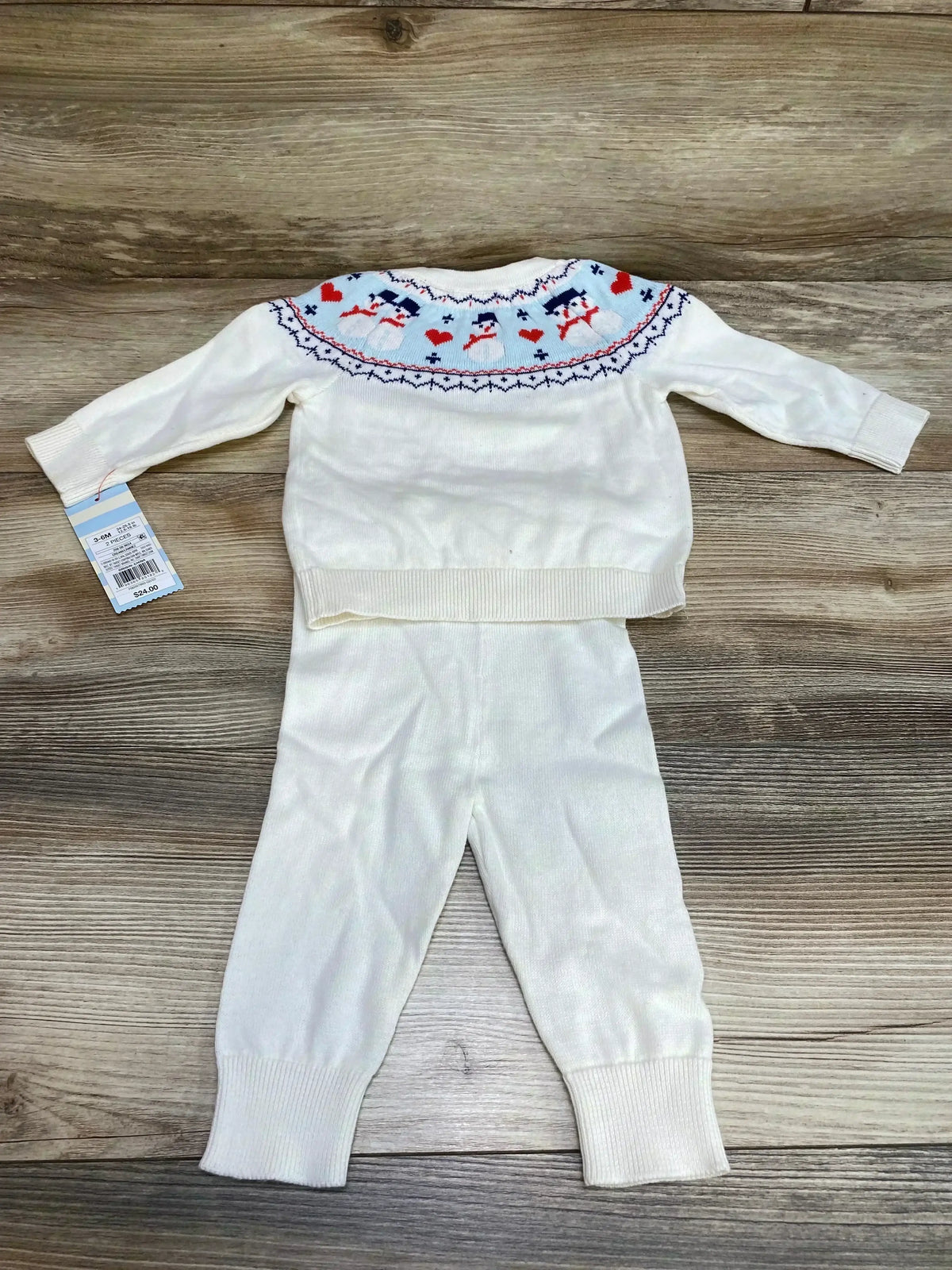 Front flat lay of Cat & Jack white 2-piece baby sweater set showing snowman Fair Isle yoke and matching ribbed pants on wood background