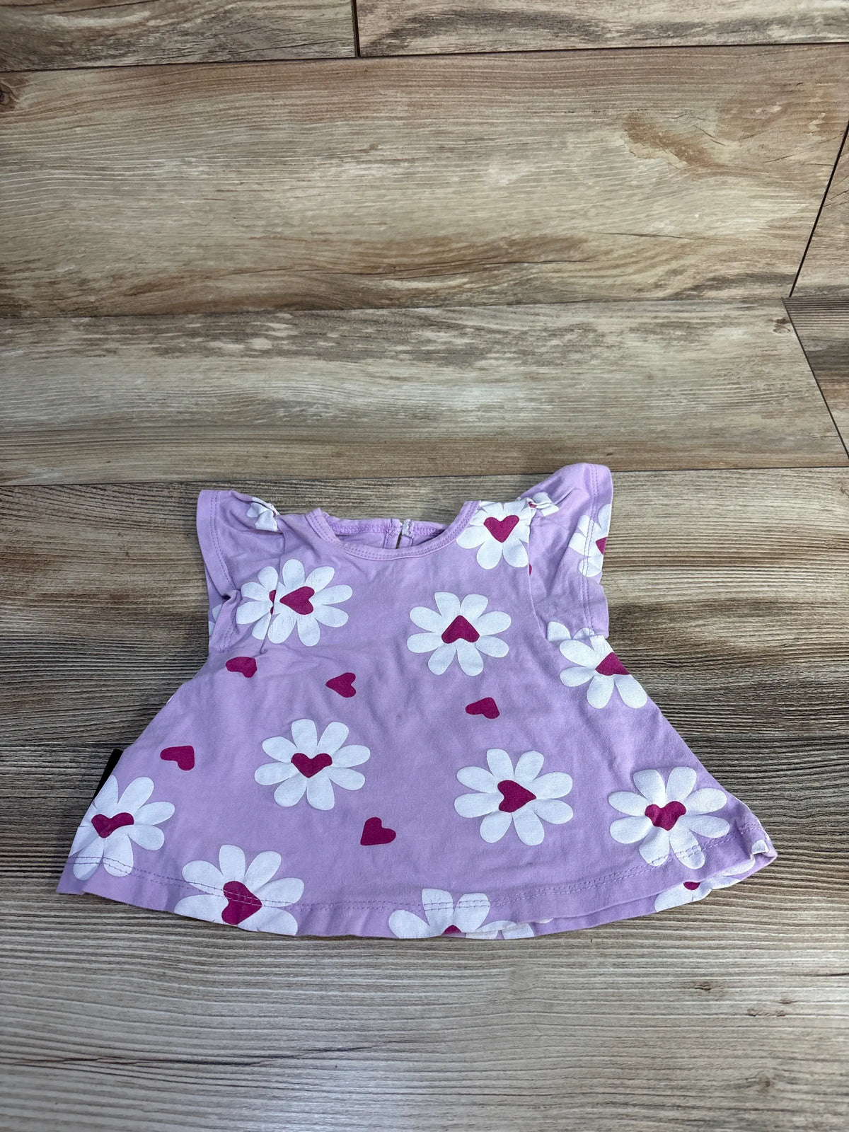 Front view of Dot Australia purple flutter sleeve shirt, size 3 to 6 months, with floral and heart print on wood background