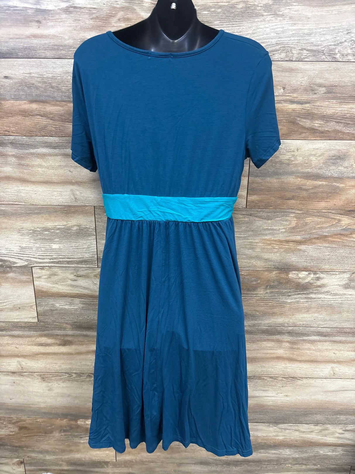 Blue short sleeve dress with a teal waistband, displayed on mannequin against wood background