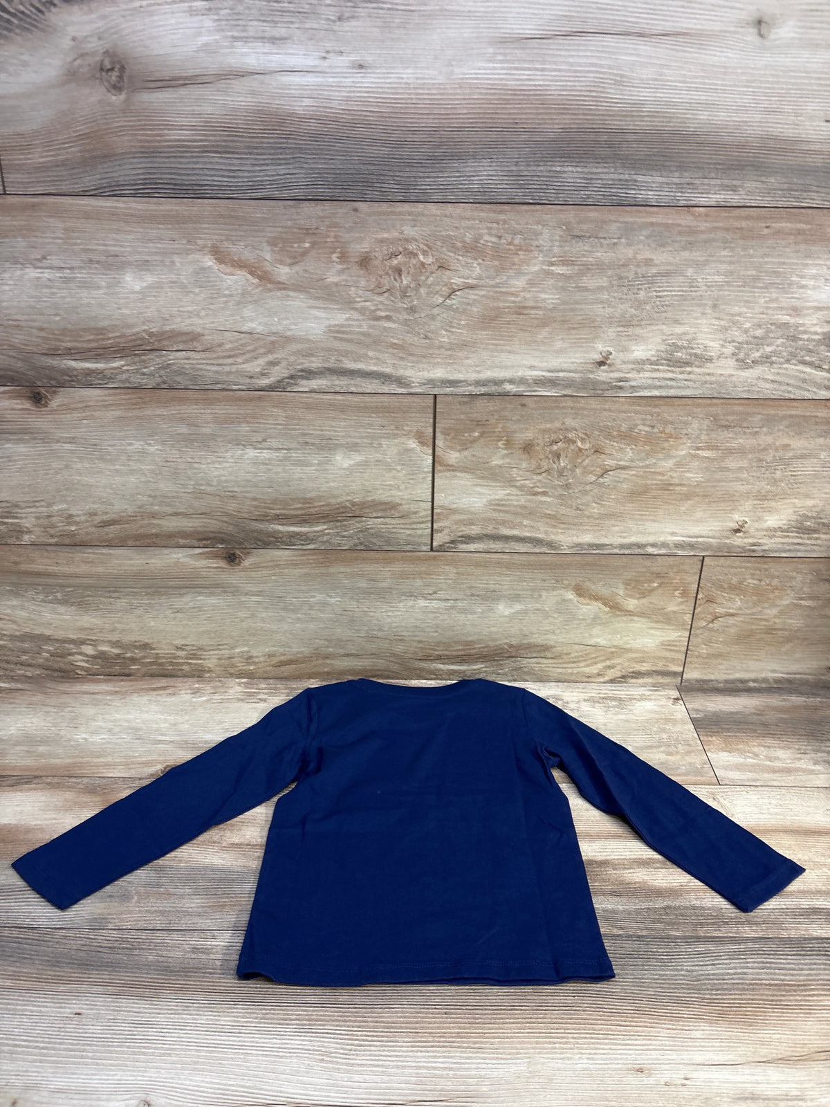 Flat-lay back view of Epic Threads navy long-sleeve toddler shirt showing solid fabric and crew neck on wood plank background