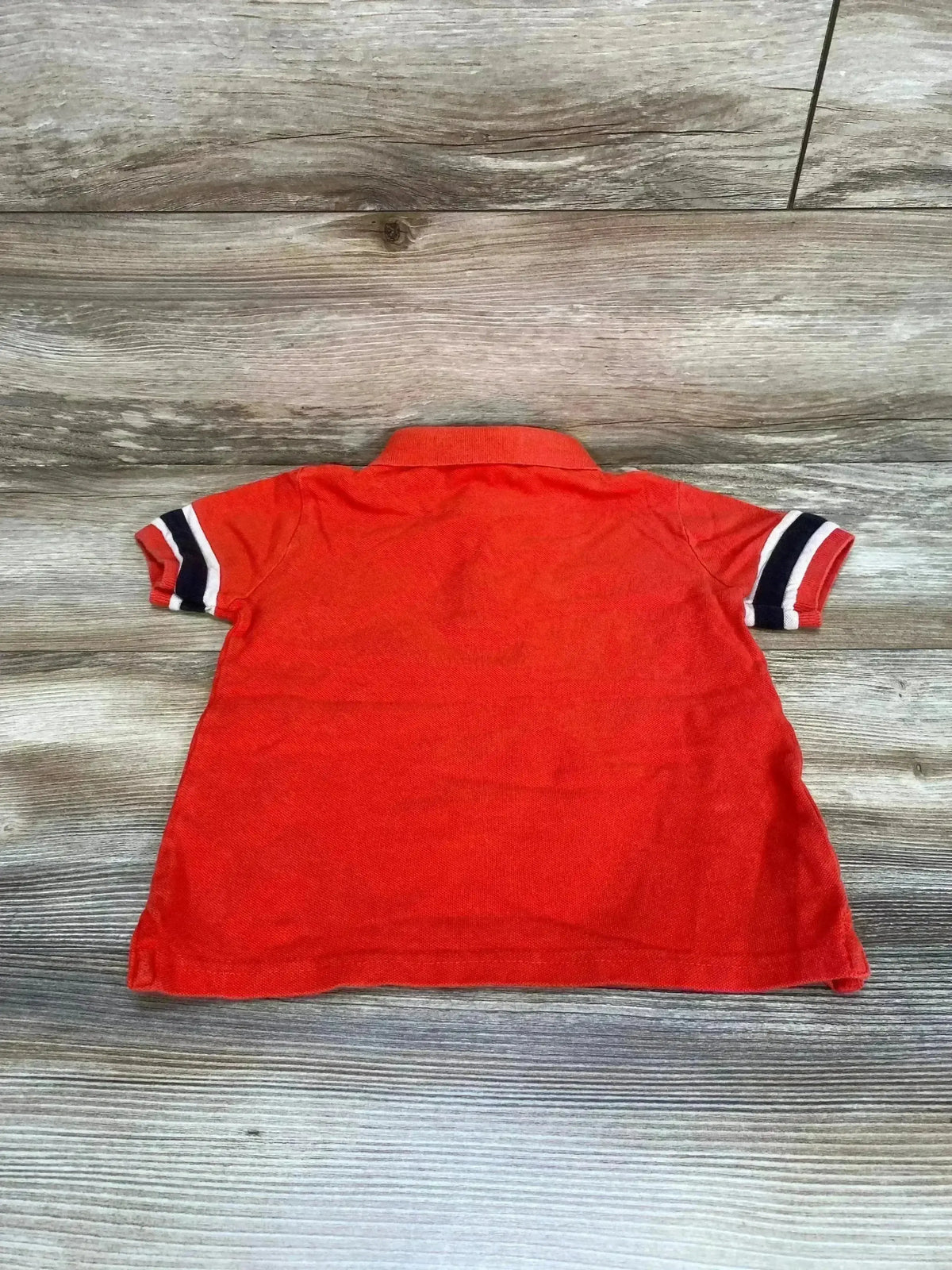 Back view of red Mayoral toddler polo shirt size 5T showing navy and white striped sleeve cuffs on wood floor background