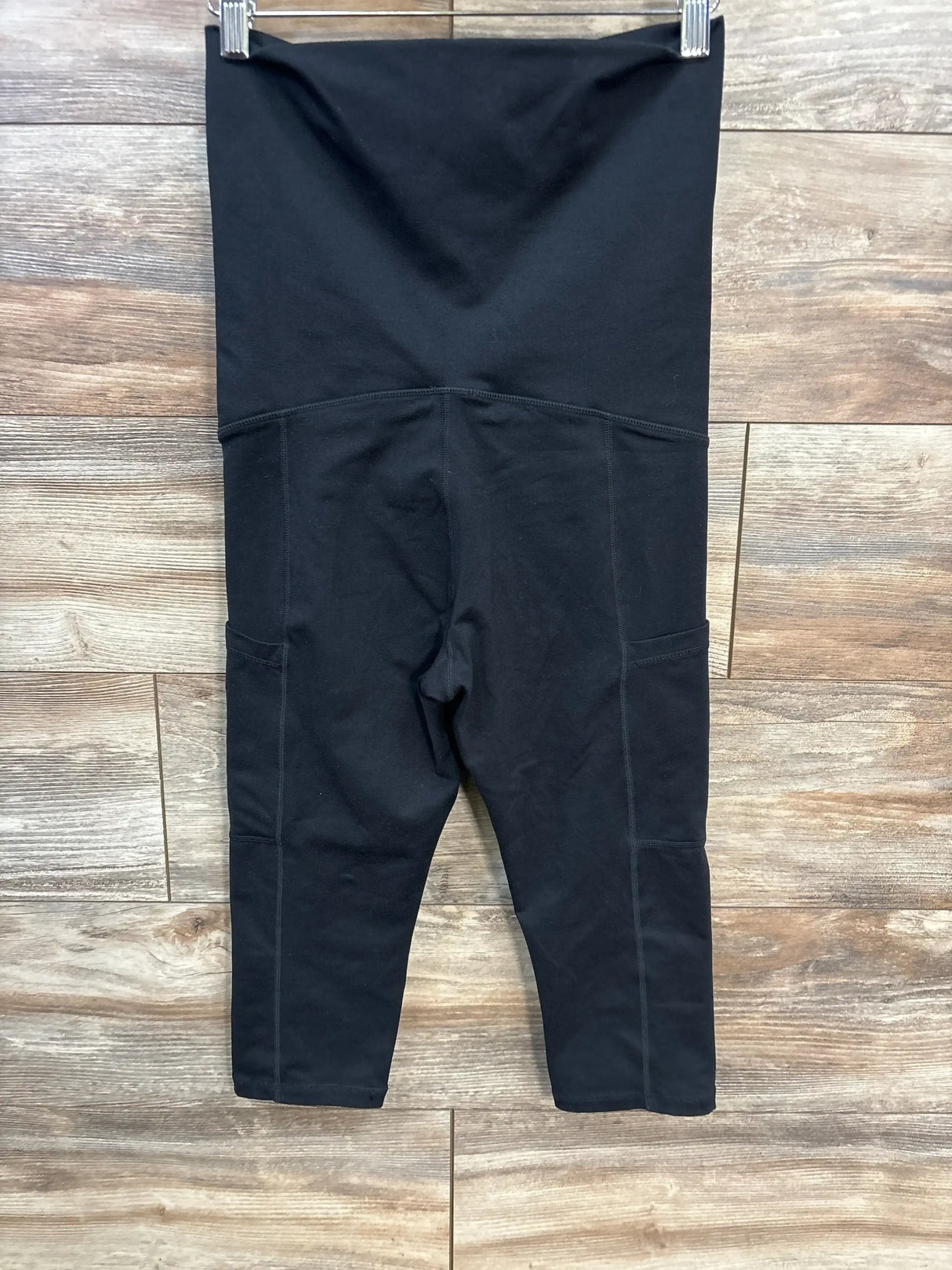 Front view of Kindred Bravely postpartum leggings, black, showing high-rise fold-over panel and pockets on wood floor