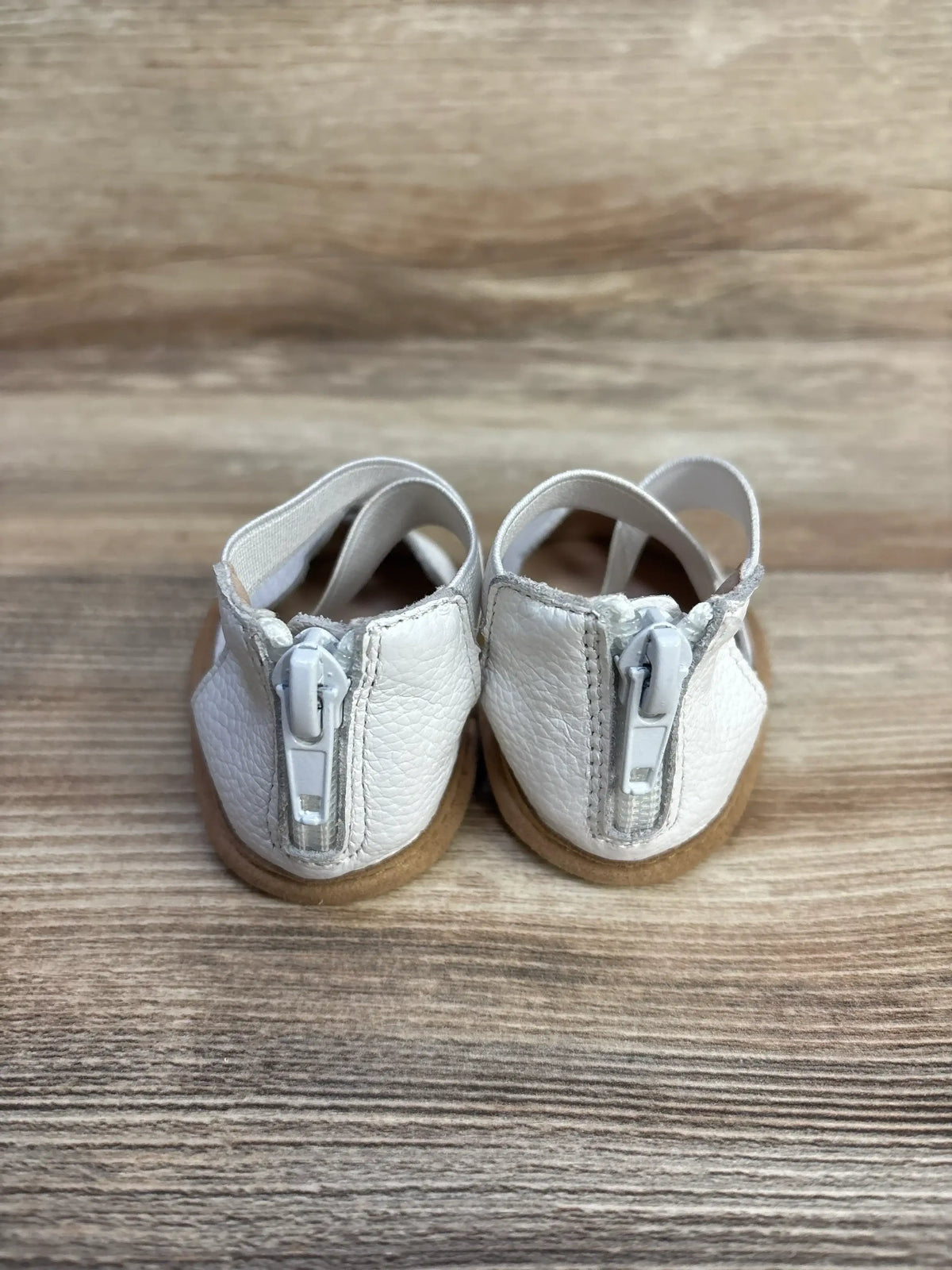 Rear view of Little Love Bug The Sophia baby shoes size 2C in white showcasing back zipper and tan sole on wood background