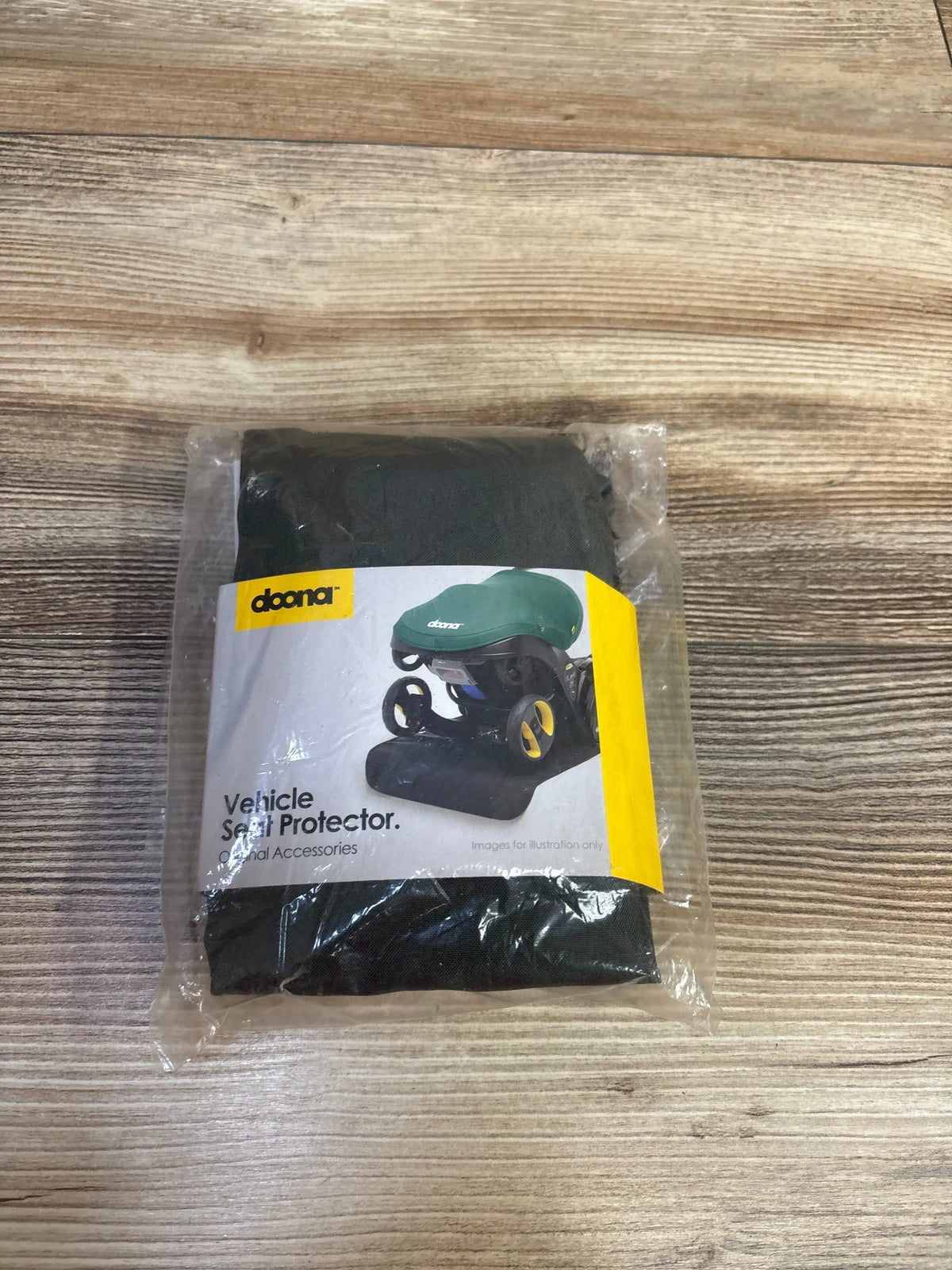 Front view of Doona Vehicle Seat Protector in green showcasing packaged protection for car seats on a wood surface