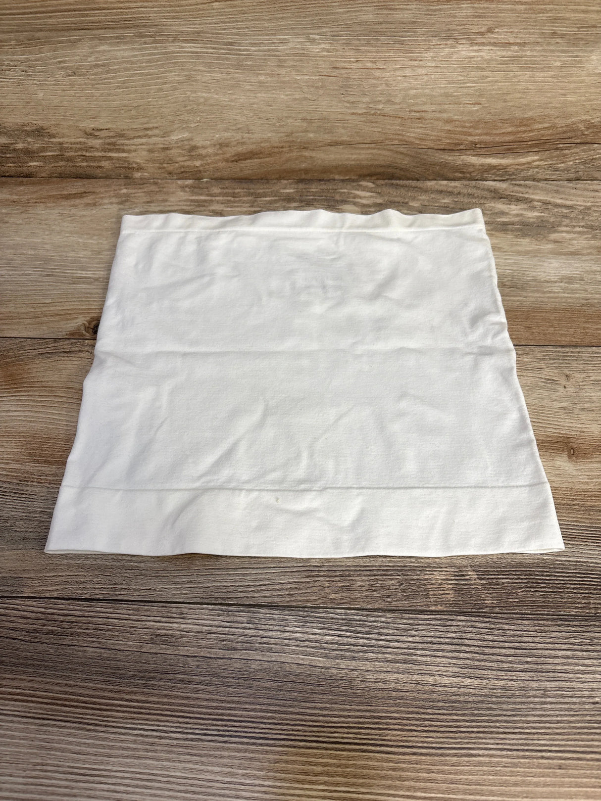 Top-down view of white Ingrid & Isabel BeBand size Small/Medium laid flat showing smooth seamless stretch band on wood background