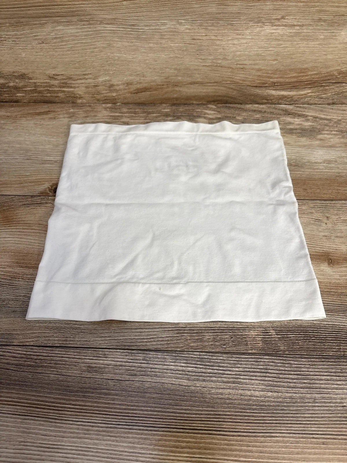 Top-down view of white Ingrid & Isabel BeBand size Small/Medium laid flat showing smooth seamless stretch band on wood background