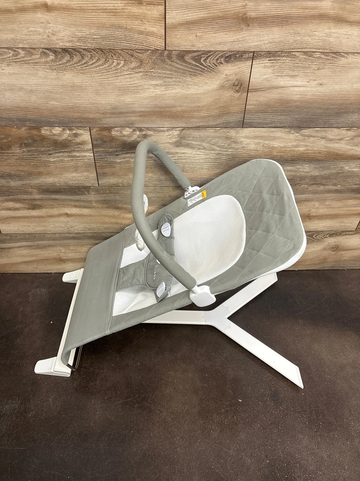 Side view of Baby Delight Alpine Deluxe bouncer in sage with quilted seat, mesh insert, toy bar, and white folding frame