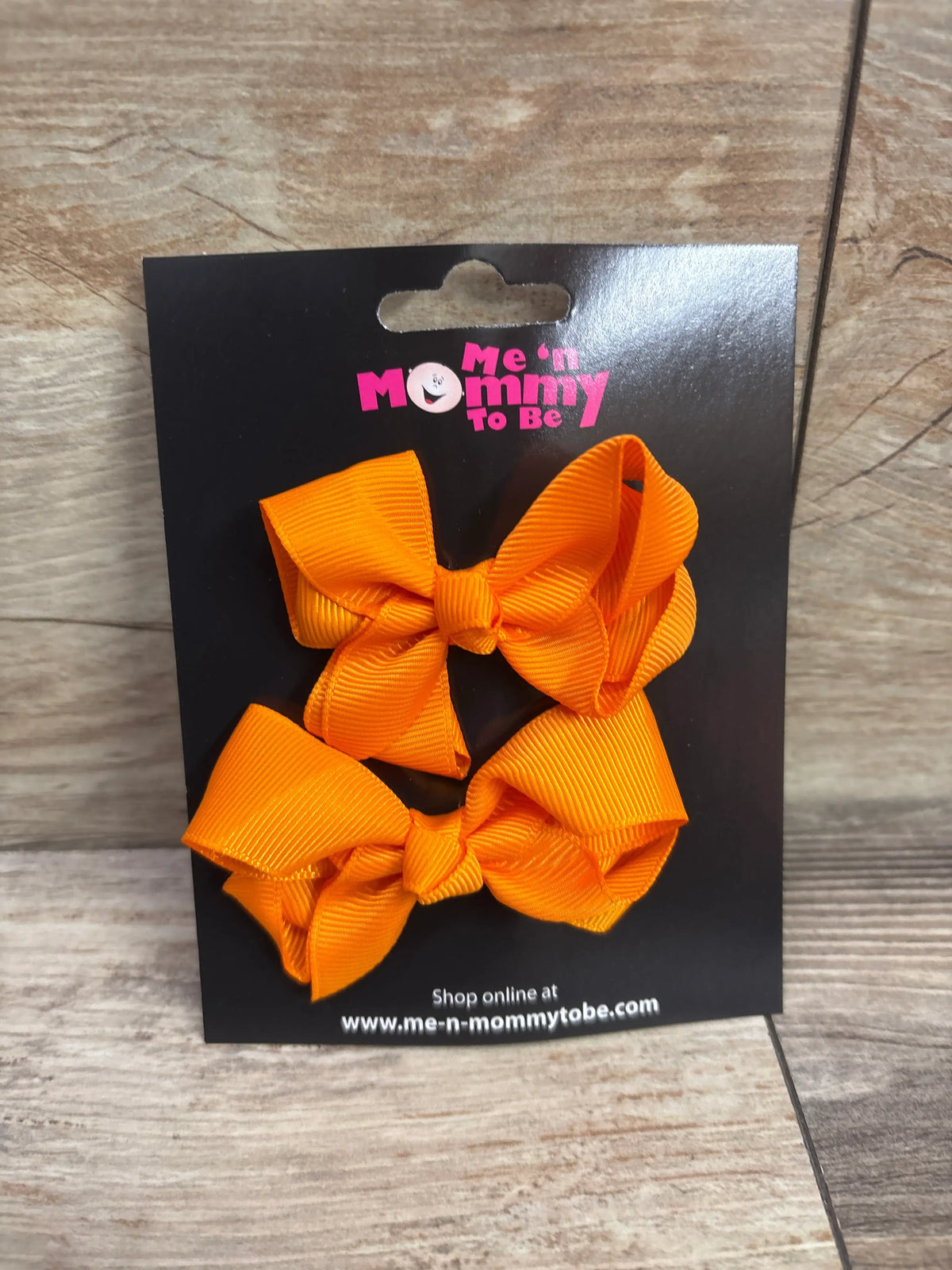 Two orange grosgrain hair bows on a Me n Mommy To Be display card.