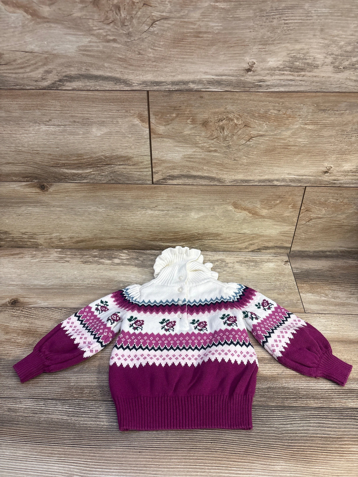 Front view of Janie & Jack Fair Isle Rose Sweater in burgundy, size 12-18m, with Fair Isle rose pattern on wood