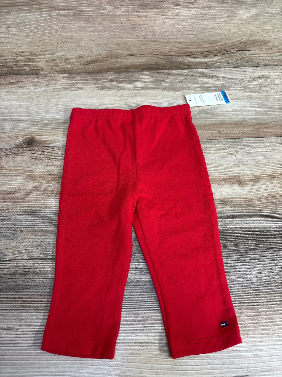 Bright red toddler pants with elastic waistband and small logo on leg, displayed on wooden floor