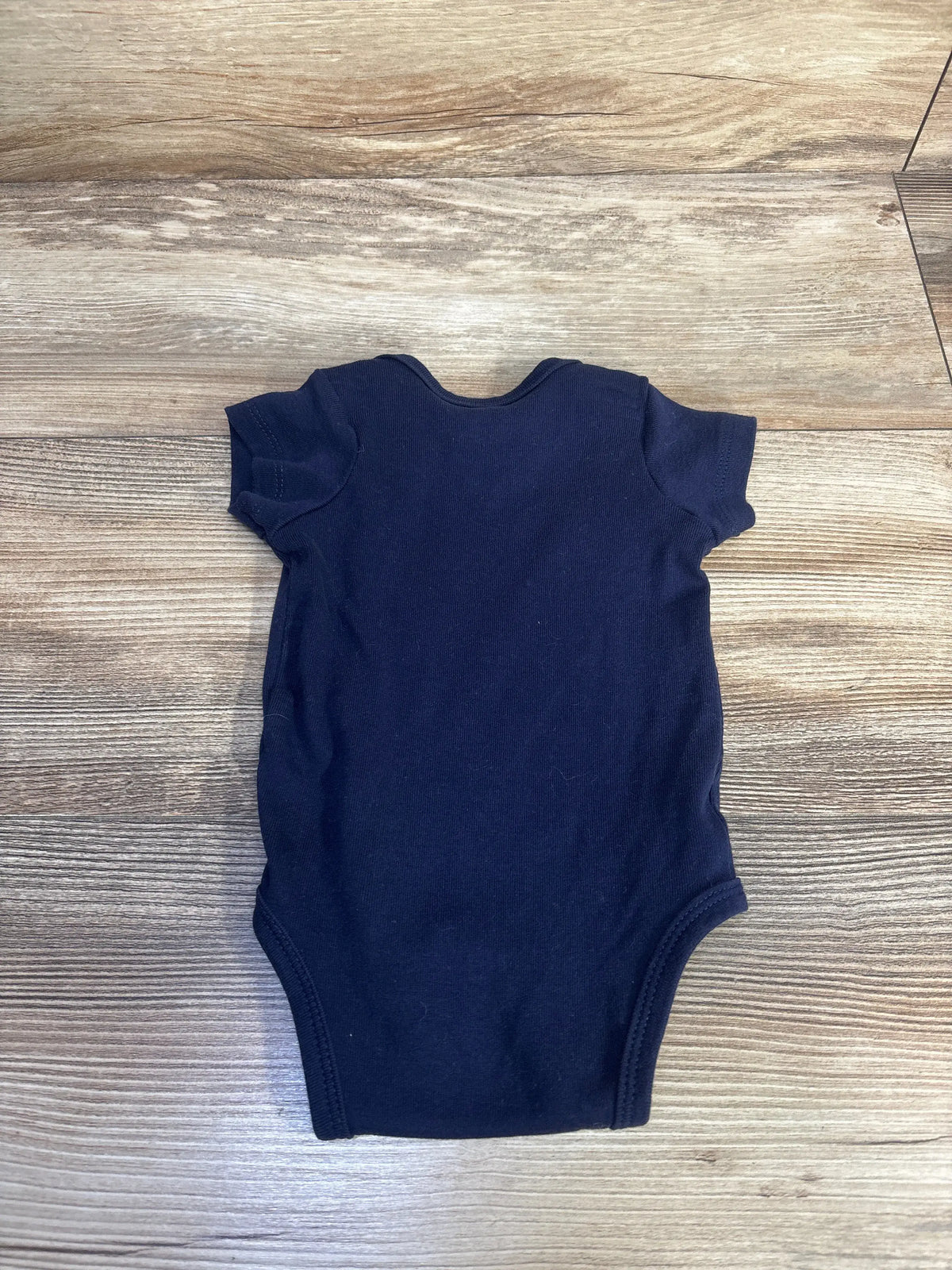 Front view of Carter’s navy bodysuit showcasing short sleeves on a wood-grain background