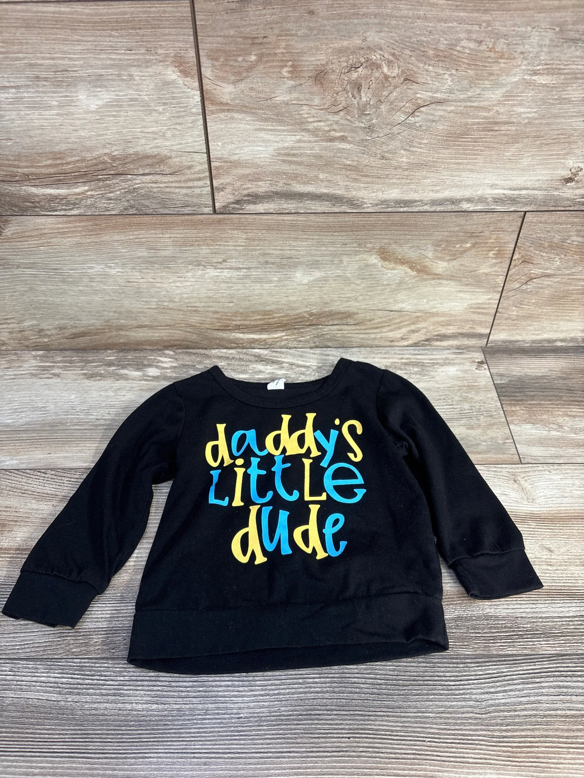 Black long-sleeve baby shirt with 'Daddy's Little Dude' in blue and yellow text.
