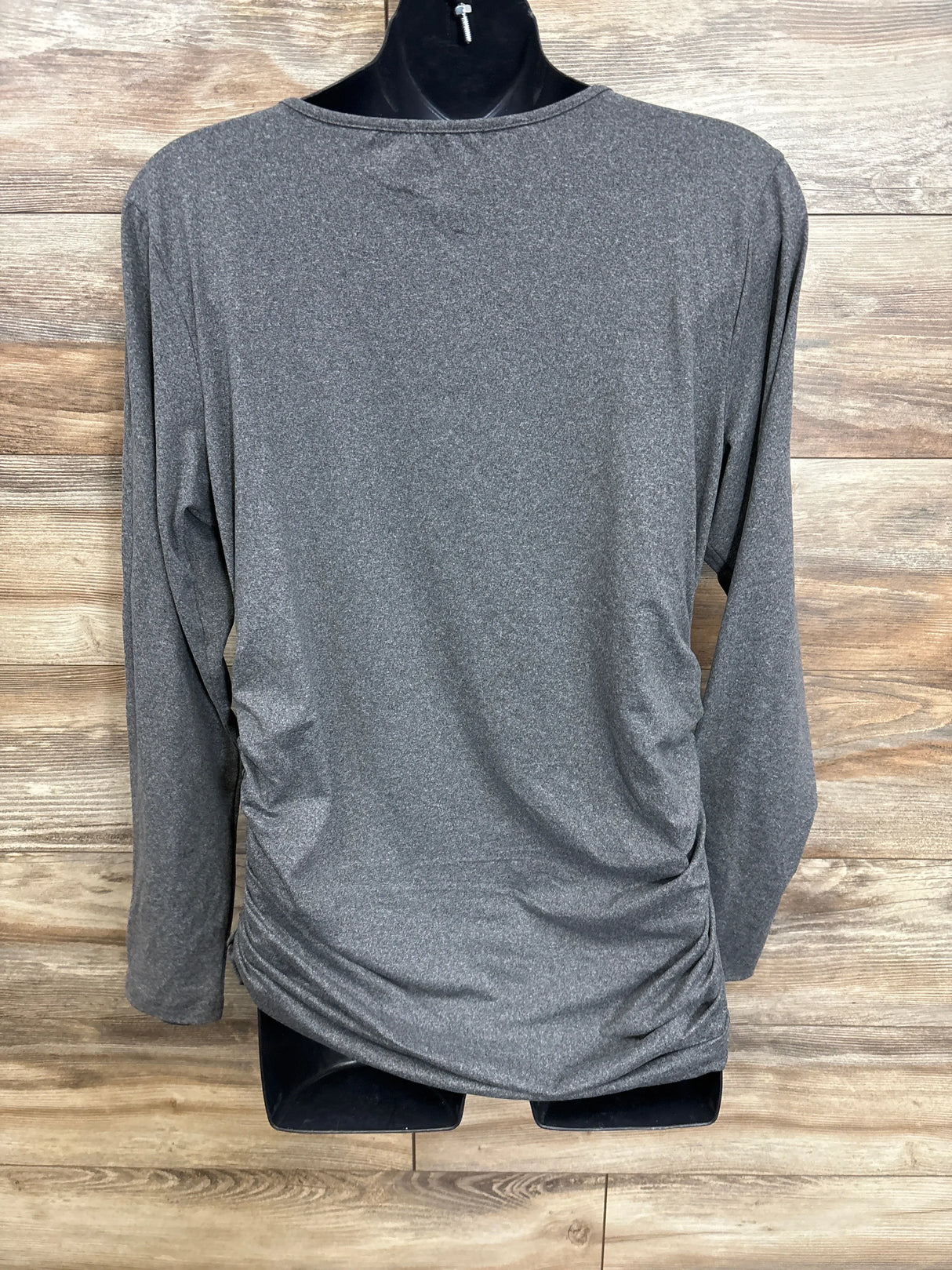 Gray long sleeve maternity top with ruched sides on mannequin, wood background