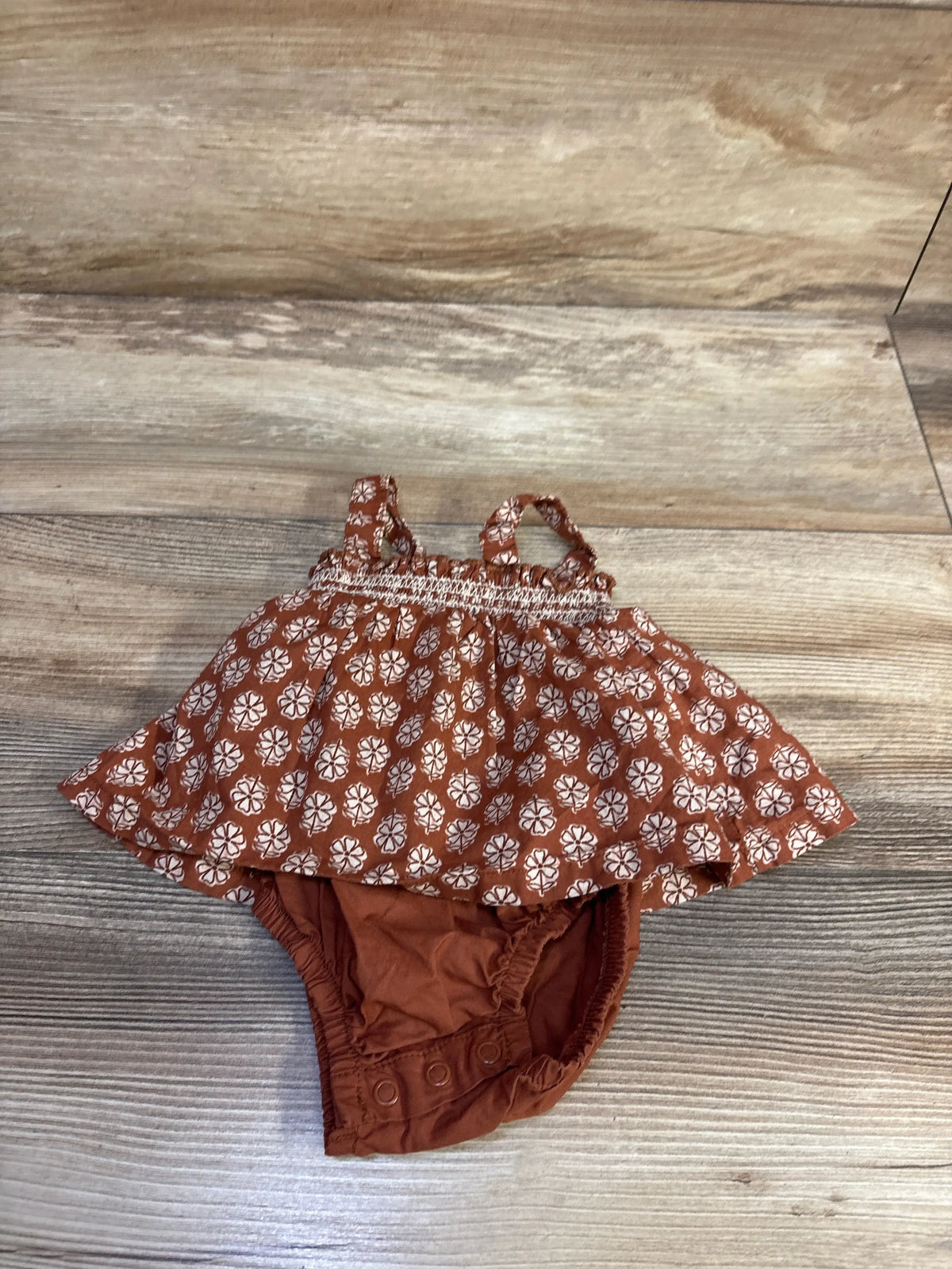 Front view of Just One You floral bodysuit dress showcasing brown fabric and floral print with a wood-look floor background