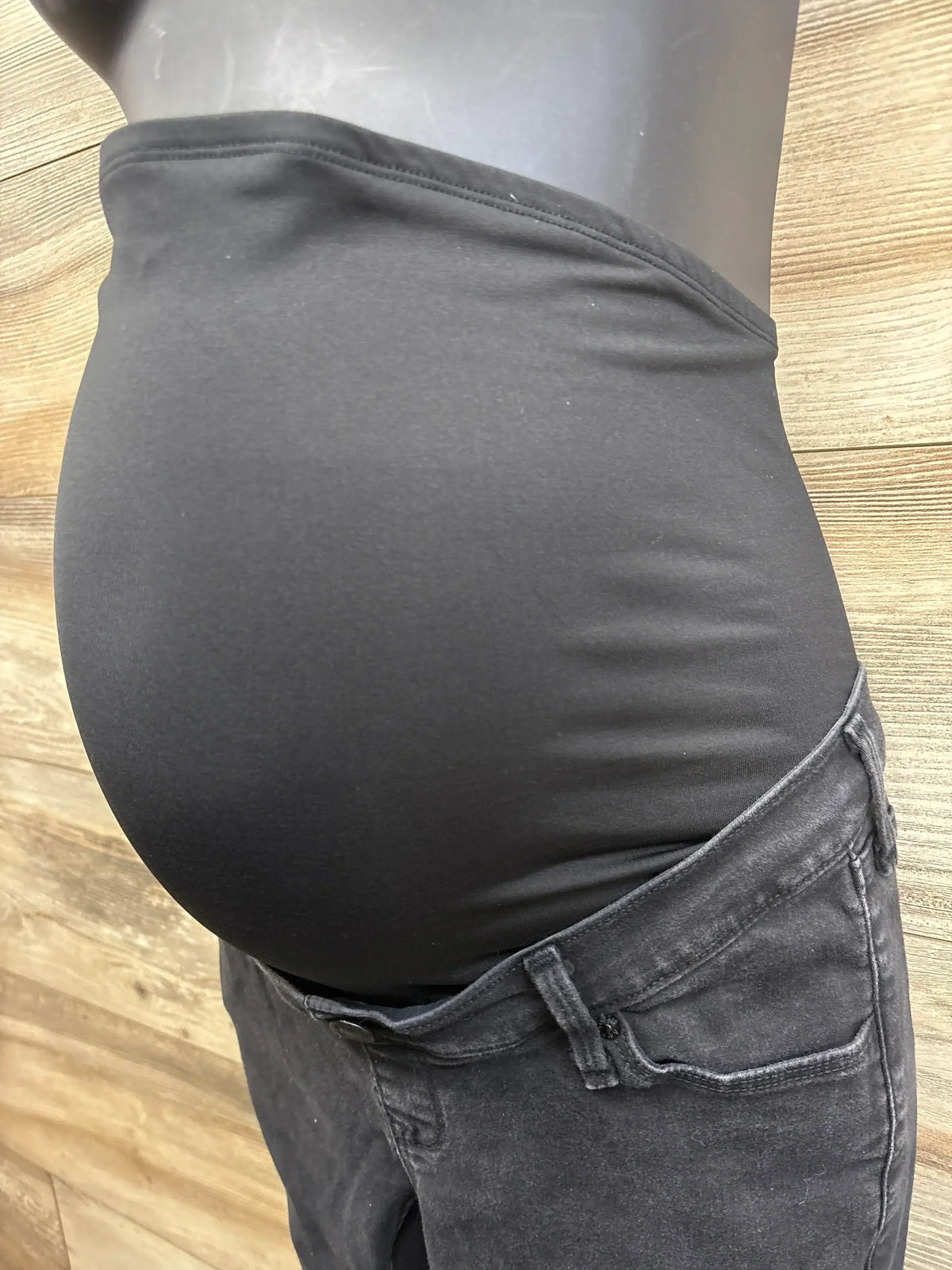 Side view of Abercrombie & Fitch black maternity jeans-leggings on mannequin showcasing full over-belly stretch panel with wood backdrop