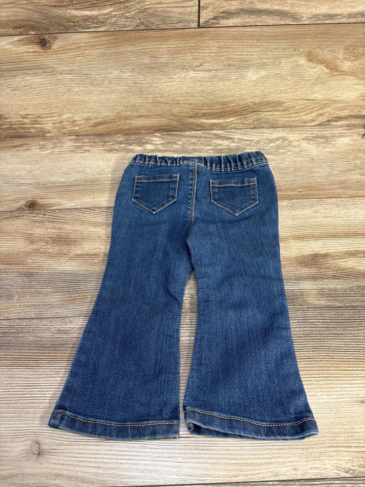 Back flat lay of Carter’s navy toddler pull-on flare jeans with elastic waistband and back pockets on wood floor