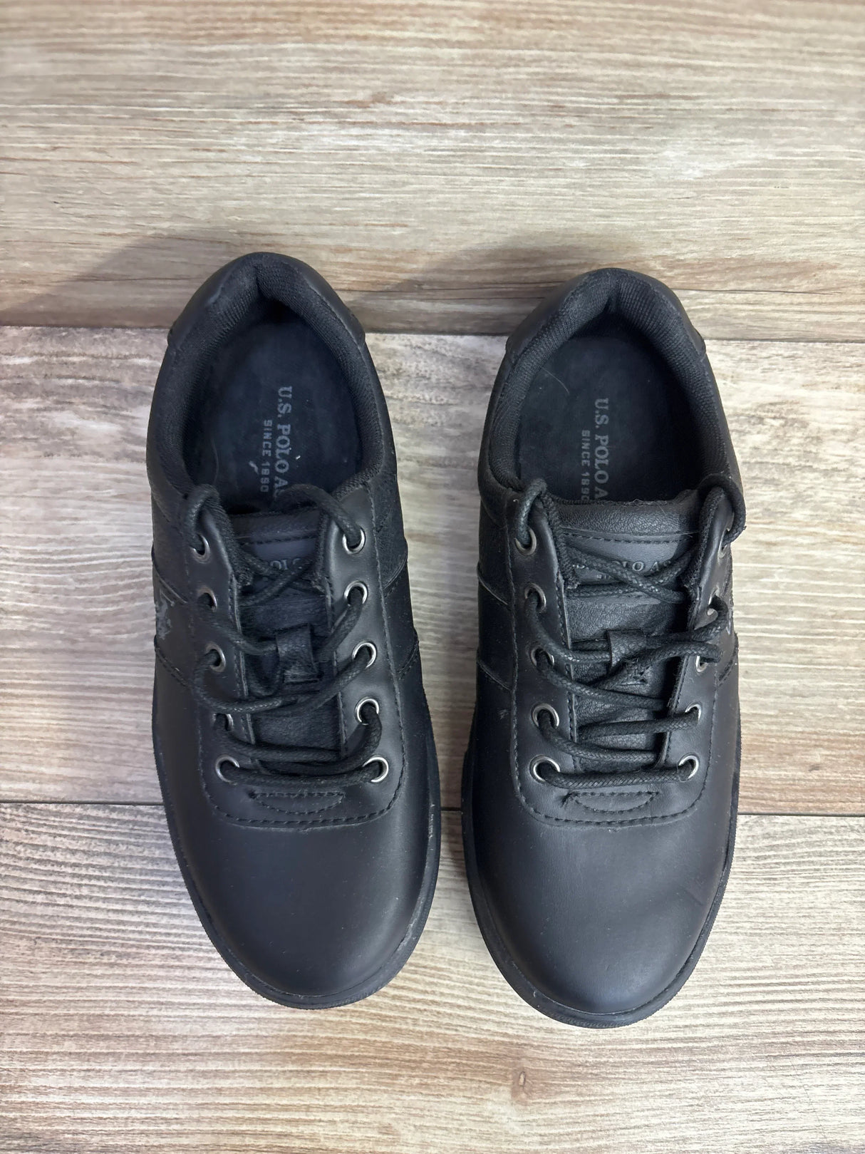 Black kids lace-up sneakers on wood floor, gently used children's shoes