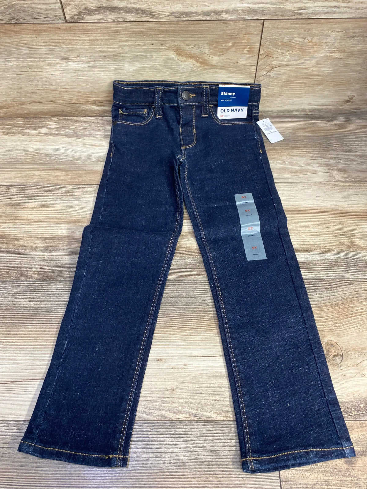 Dark wash kids skinny jeans with pockets and tags displayed on wood floor