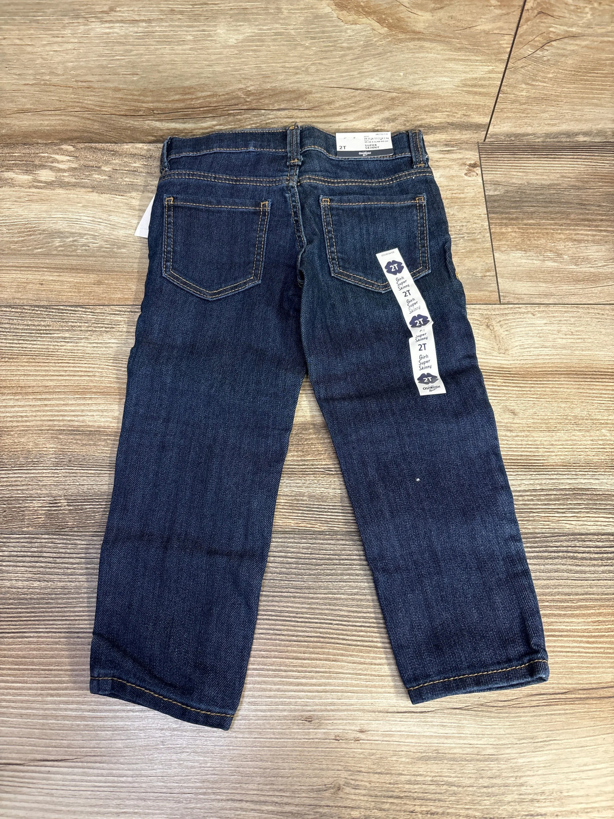 Dark wash toddler jeans size 2T with back pockets on wood floor, resale kids clothing.