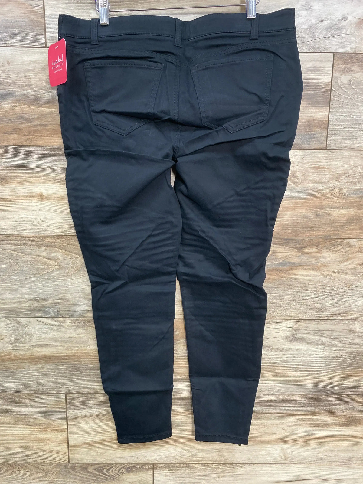 Black maternity pants with back pockets and tag, laid flat on wooden floor