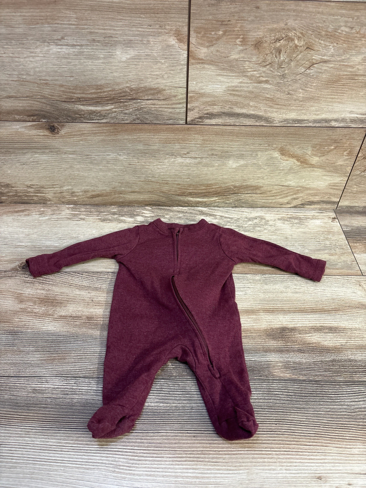 Flat lay of newborn Old Navy footed sleeper showcasing diagonal front zipper and long sleeves with wood plank background