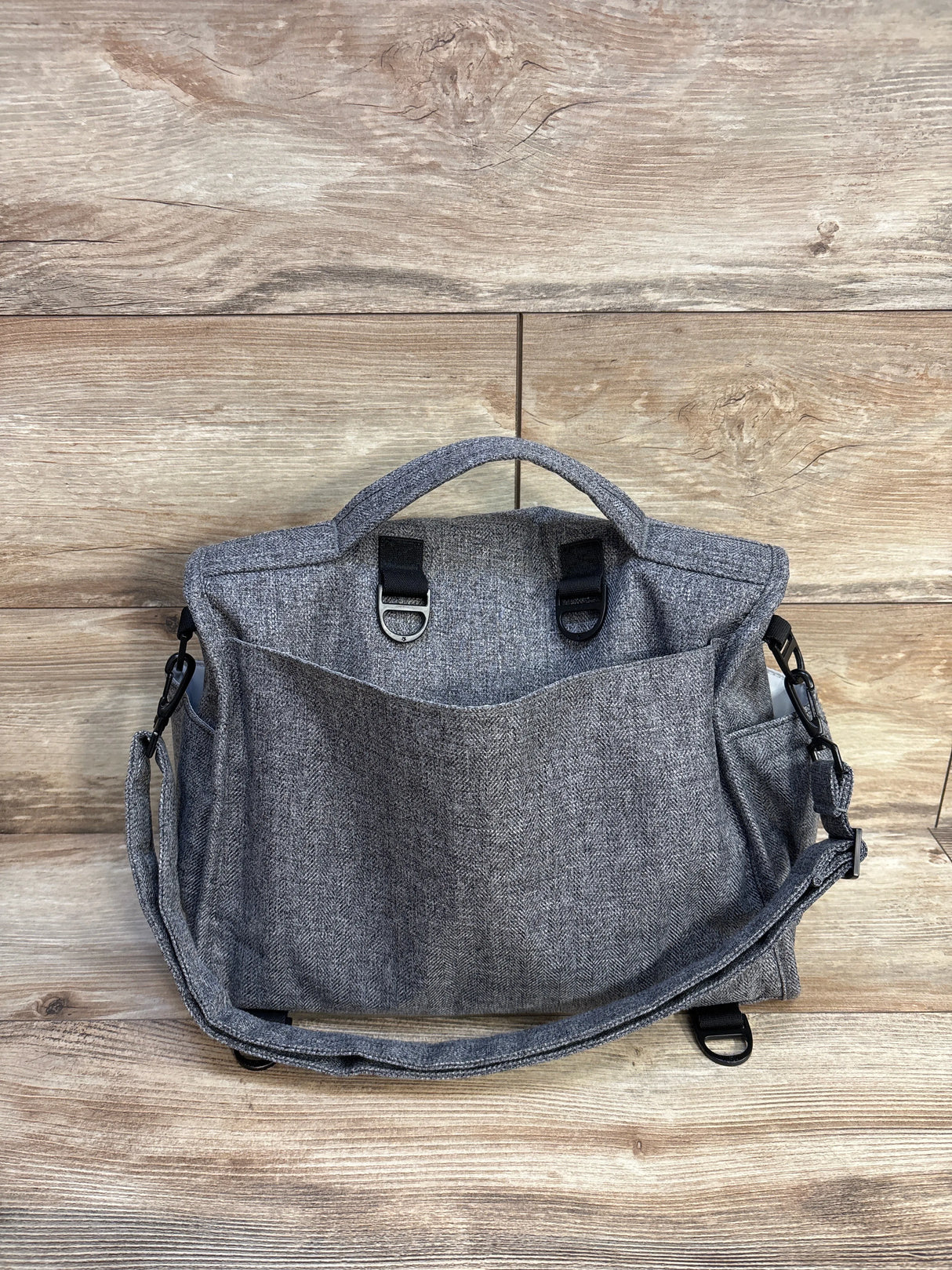 Gray fabric messenger bag with front pocket and shoulder strap on wood background