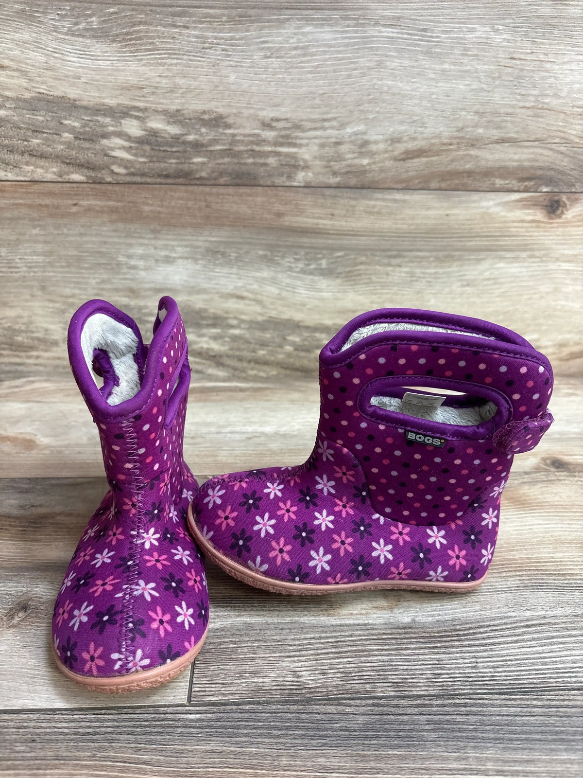 Purple Bogs toddler boots with pink flower and polka dot pattern on wood floor