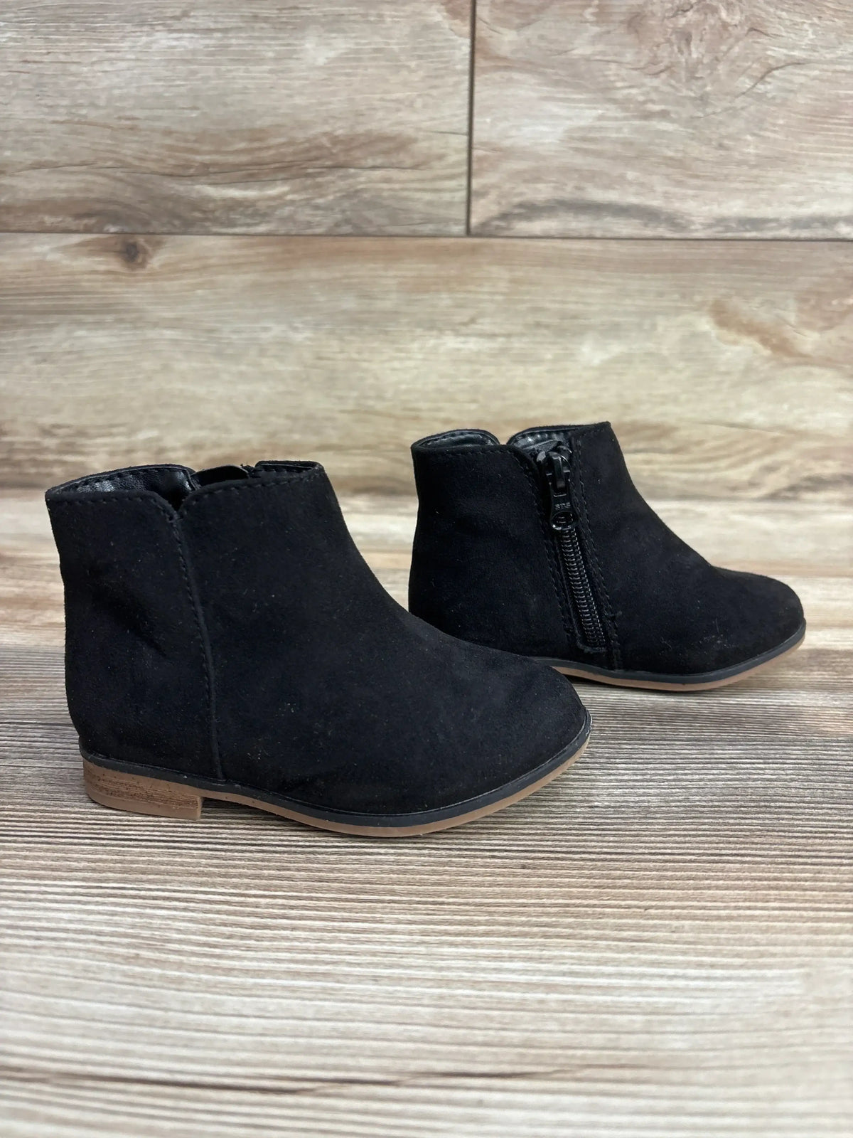 Pair of black toddler ankle boots with side zipper on wooden surface, kids shoes