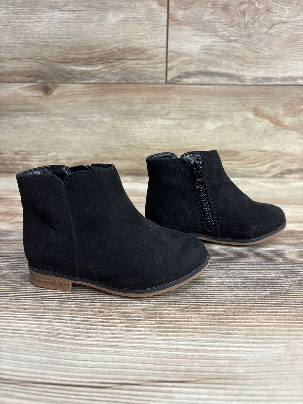 Pair of black toddler ankle boots with side zipper on wooden surface, kids shoes