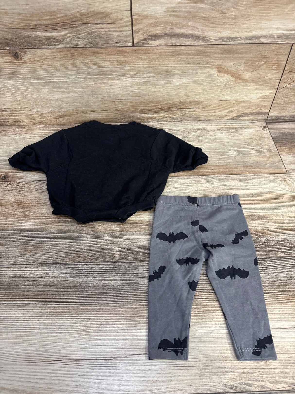 Black baby onesie with gray bat-print leggings, kids Halloween outfit on wood floor