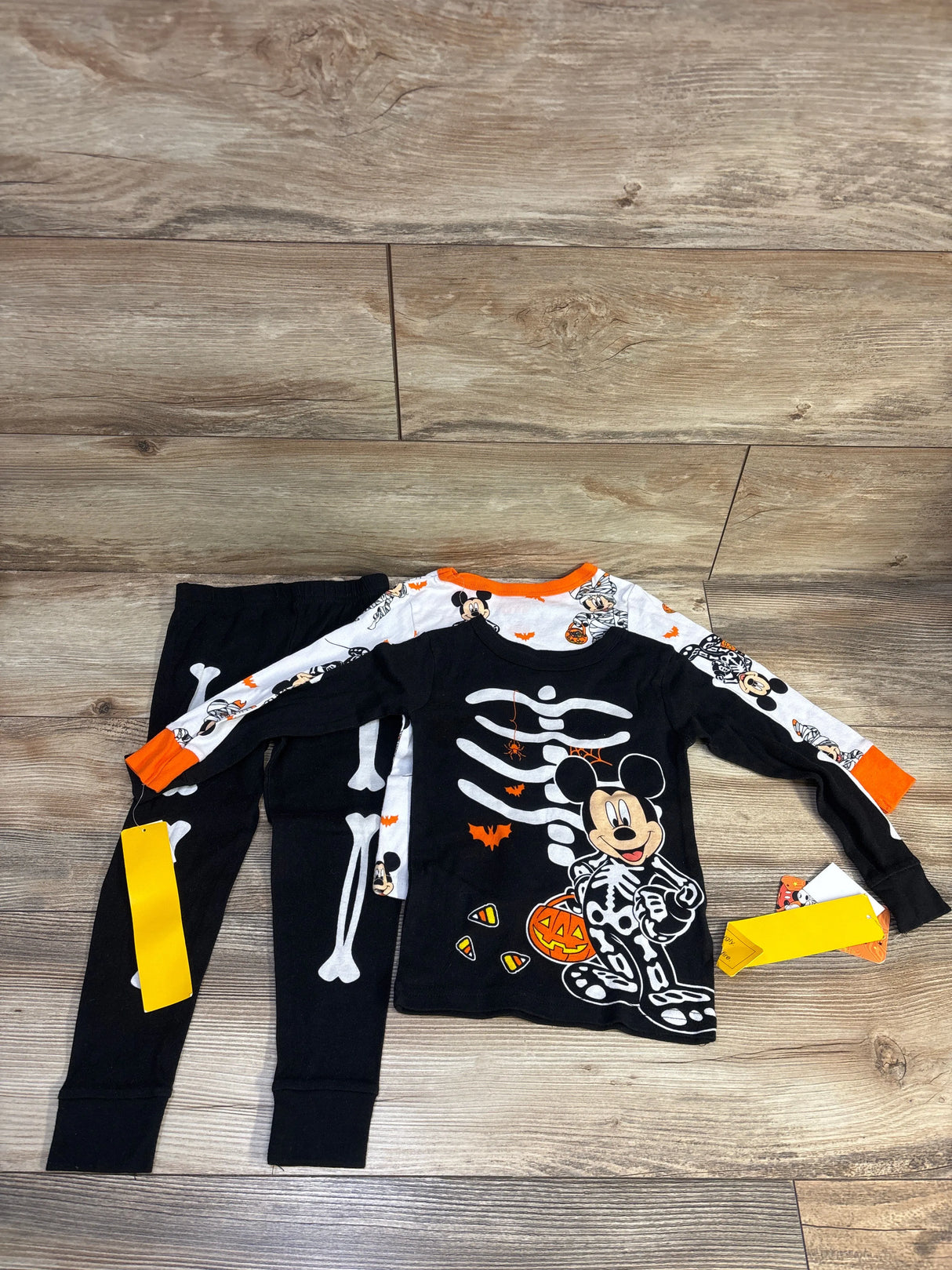 Flat lay of 3-piece Mickey Mouse toddler Halloween pajamas size 4T showing black skeleton-print top and bone-print leggings