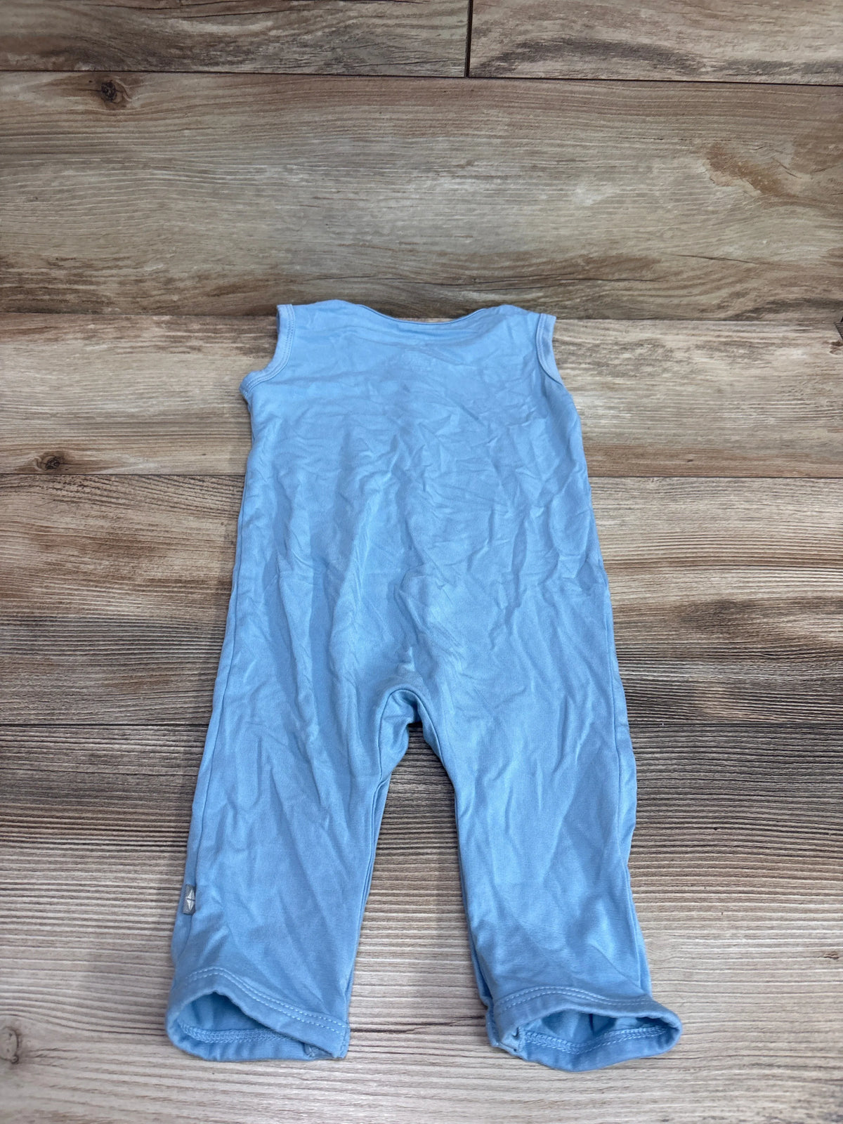 Kyte Baby sleeveless snap jumpsuit in light blue for infants, laid flat on a wood floor.