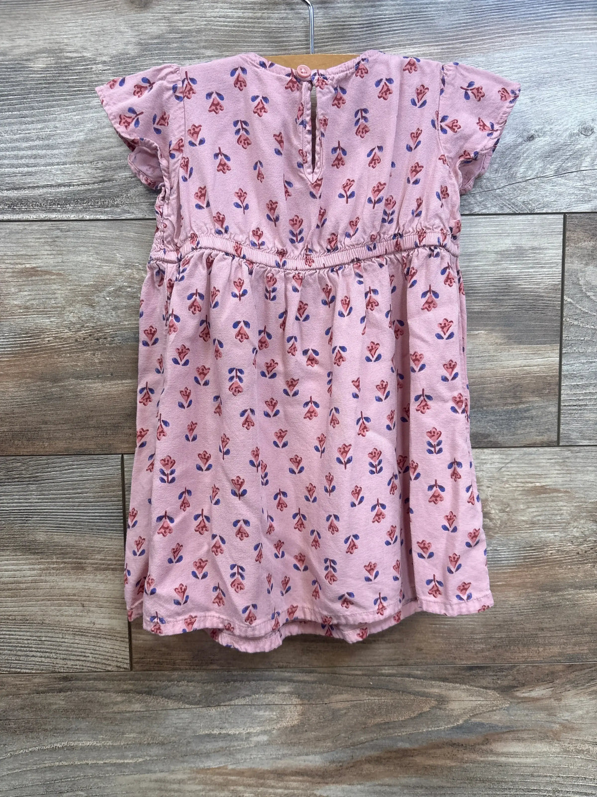 Front view of Carter’s pink floral viscose dress, size 18 months, with short sleeves, cinched waist, keyhole button, on wood floor